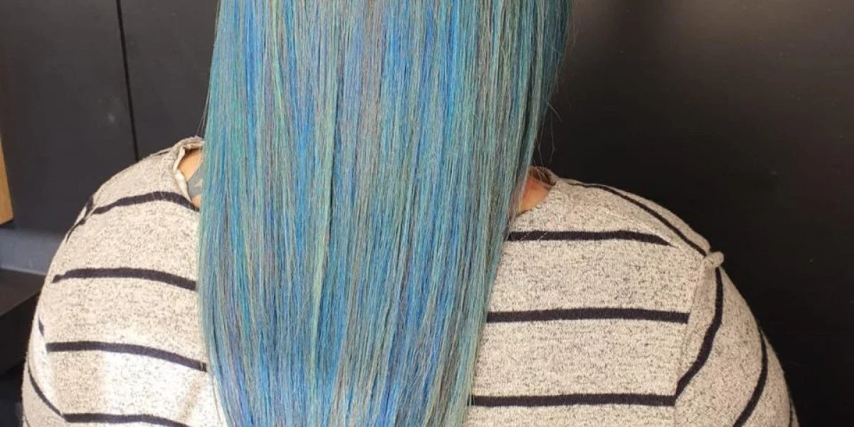 Person with long, straight, blonde hair, wearing a navy-blue shirt, in a salon setting.
