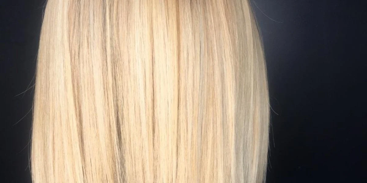 A woman with shoulder-length, curly, peach-blonde hair standing in front of a white wall with black text.