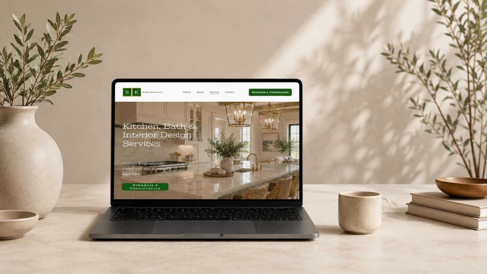 Laptop displaying the Studio Kinon website on a neutral workspace with greenery and ceramic decor.