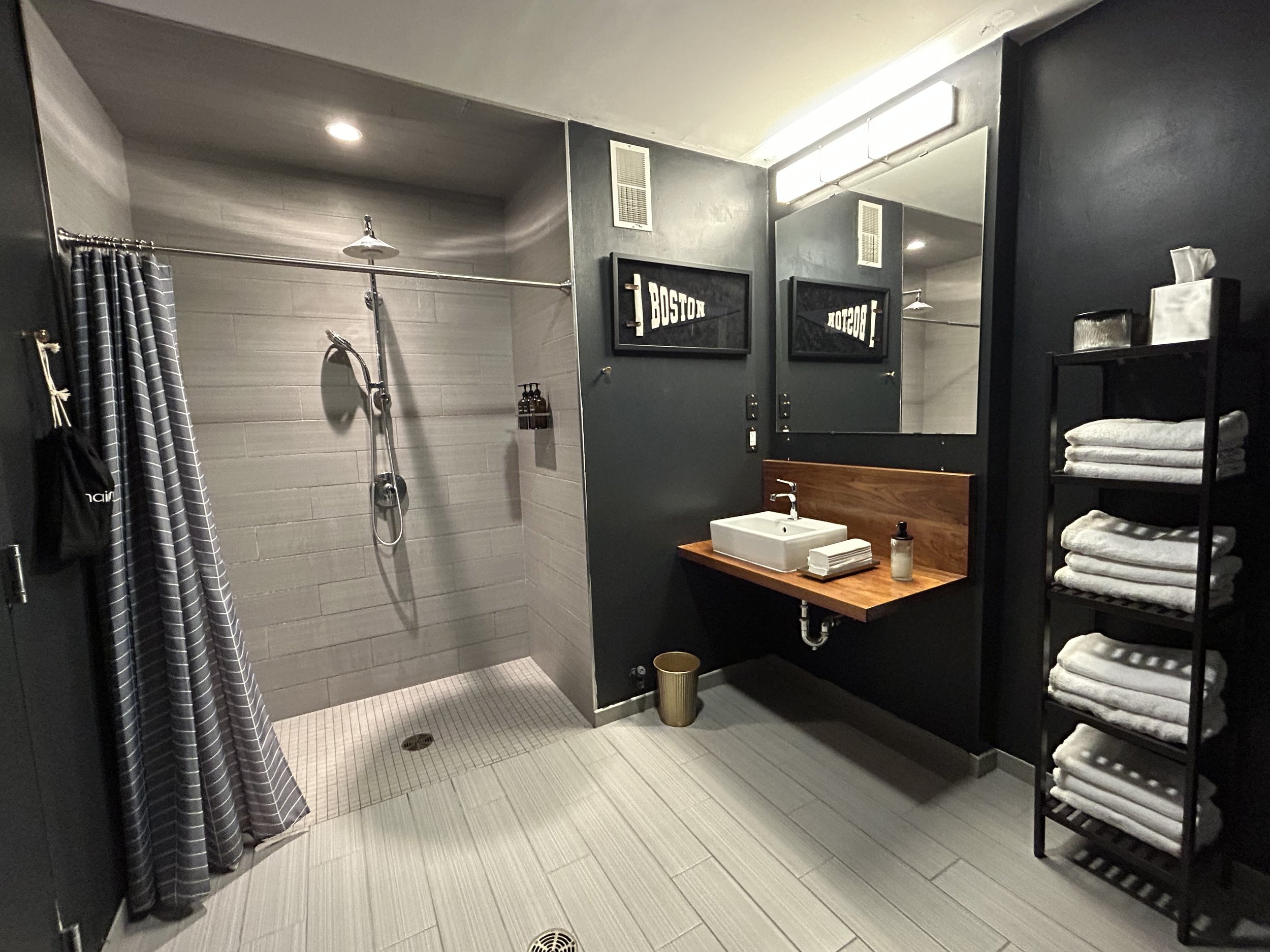 Upscale, modern private client restroom featuring a pristine personal shower, fresh towel service, and premium grooming products.