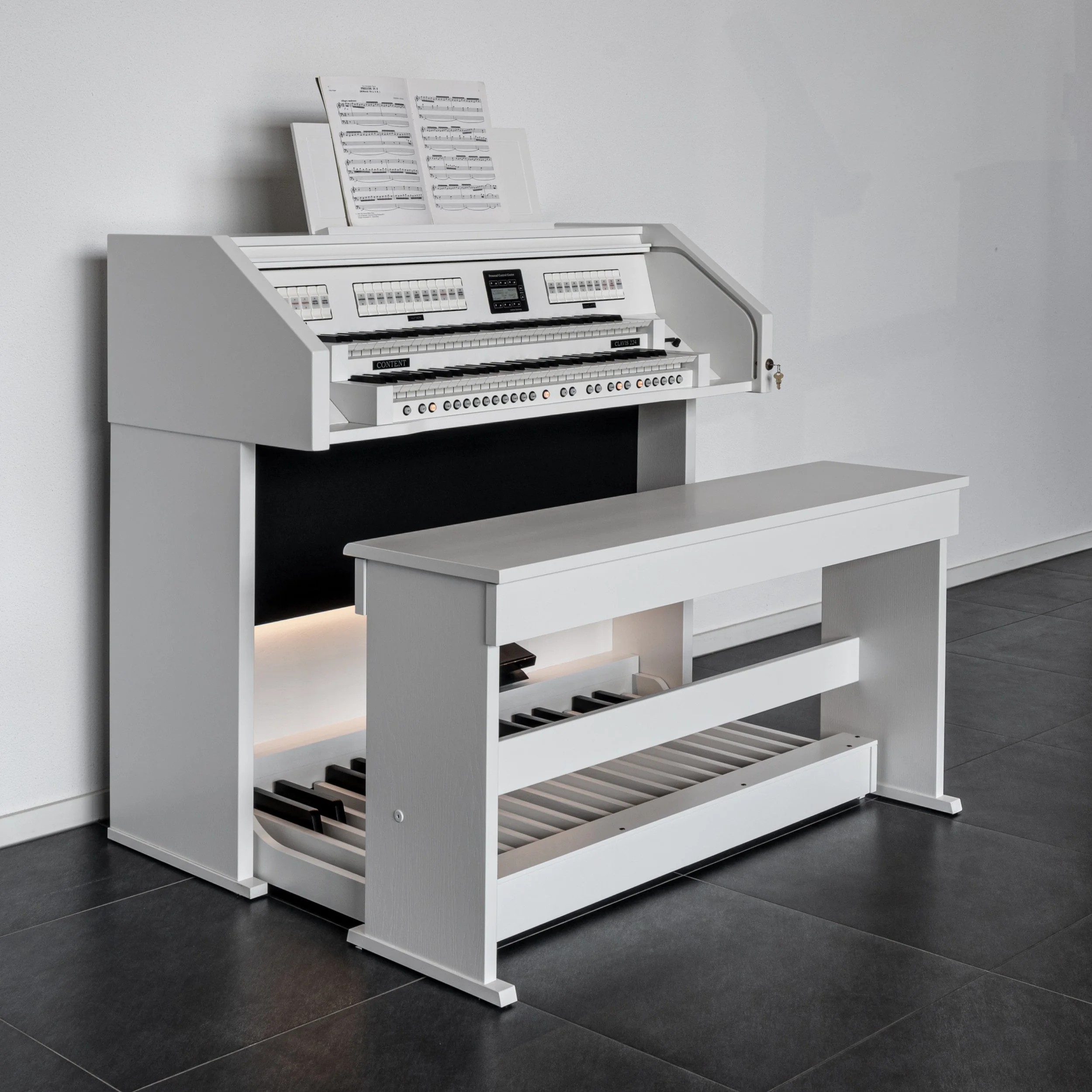 A white upright piano with music sheets on top, positioned against a white wall, with a matching white bench in front of it.