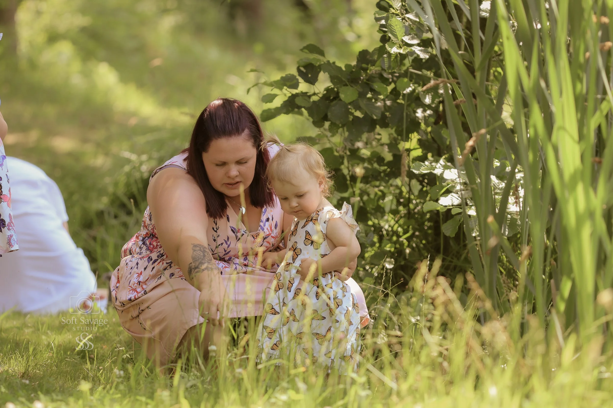 Eine Frau und ein kleines Mädchen, Keks oder Blumen pflückend, im Grünen, bei Sonnenschein, im Freien