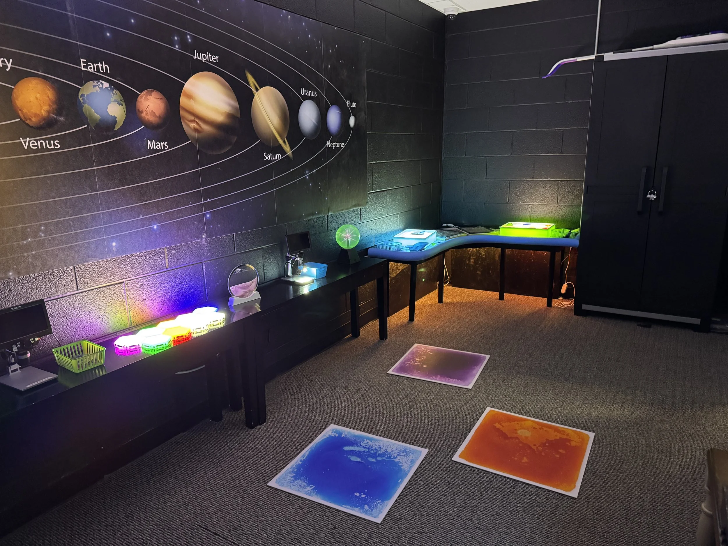 A dark room with light boxes and a poster of the solar system on the wall