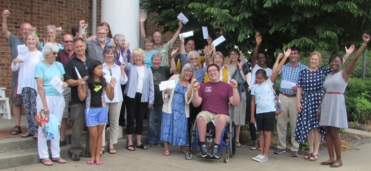 A group poses with their arms in the air