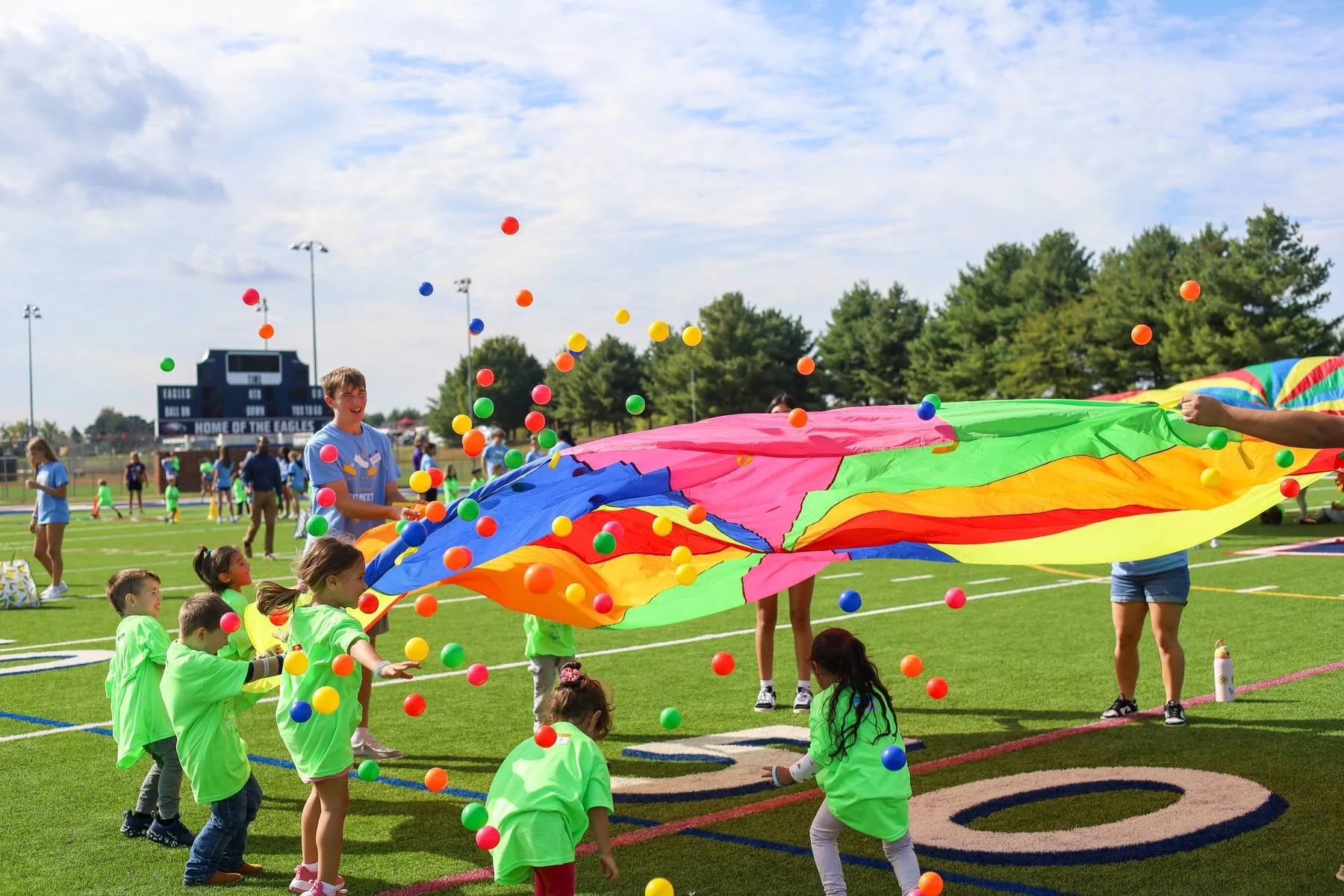 Children play with a brightly colored parachute