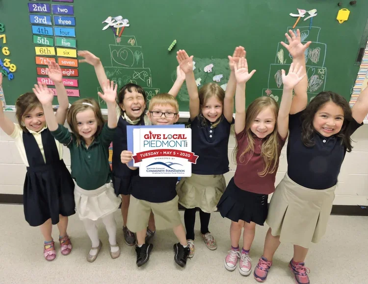 Children pose with a Give Local Piedmont Sign