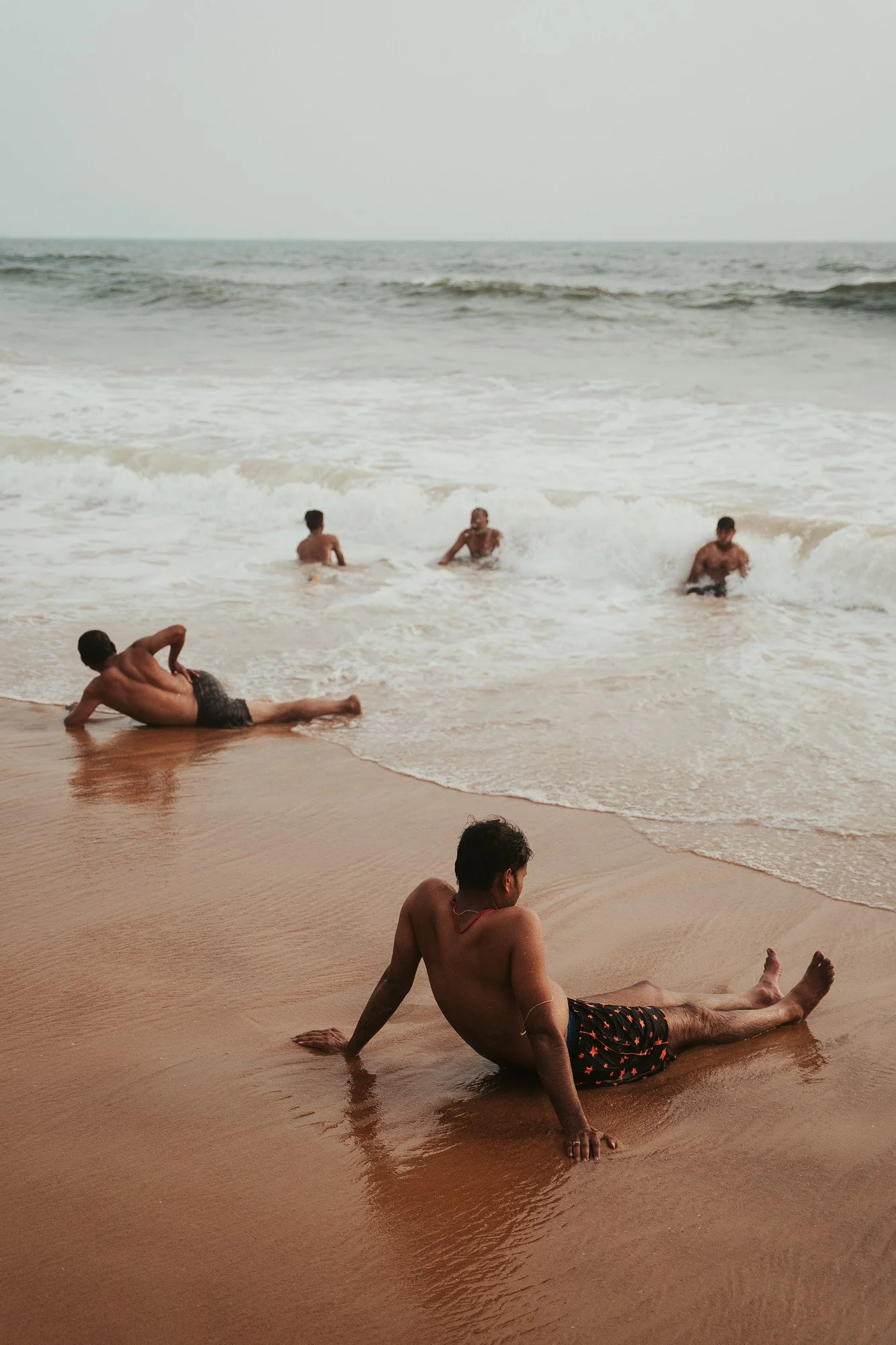 People relaxing and playing in the ocean on a sandy beach during daytime.