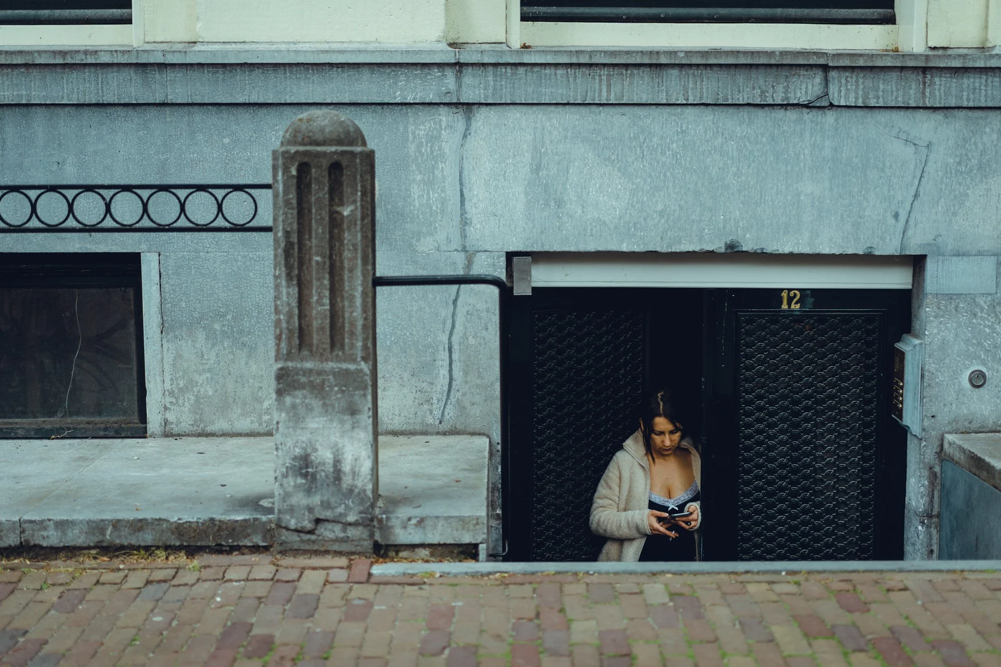 A woman is standing in an underground parking garage, looking at her phone.