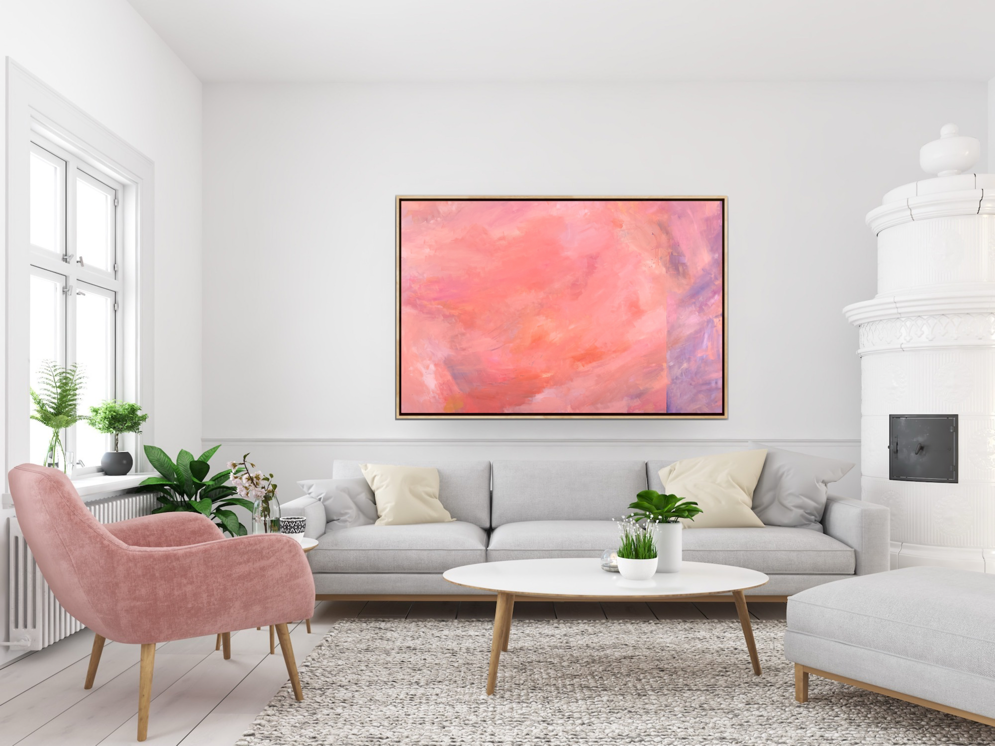 Living room with white walls, large window with plants, gray sofa with white and beige pillows, pink armchair, oval coffee table with plants, abstract pink and purple painting by Jocelyn Elizabeth on wall, white textured stove on right.