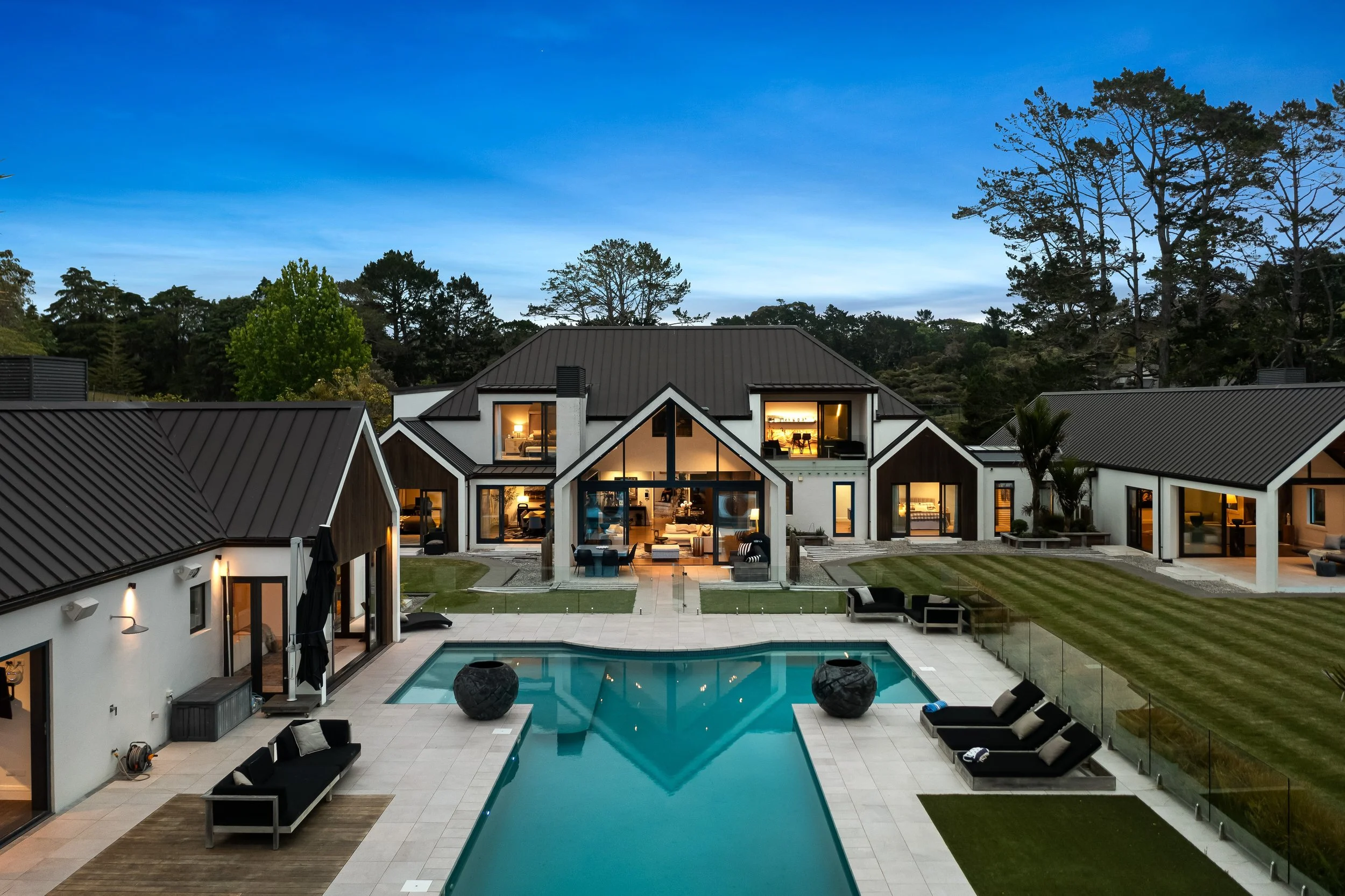 Ultra-high-end Rodney estate with pavilion-style architecture, resort-style pool, landscaped grounds, and expansive indoor-outdoor living at dusk