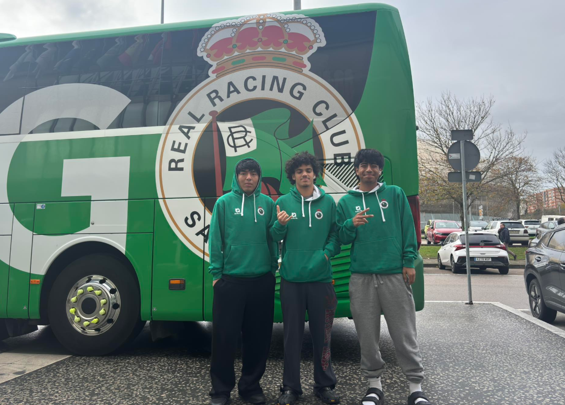Three young men standing in front of a large green bus with the logo of the Royal Racing Club on it. They are wearing matching green hoodies.