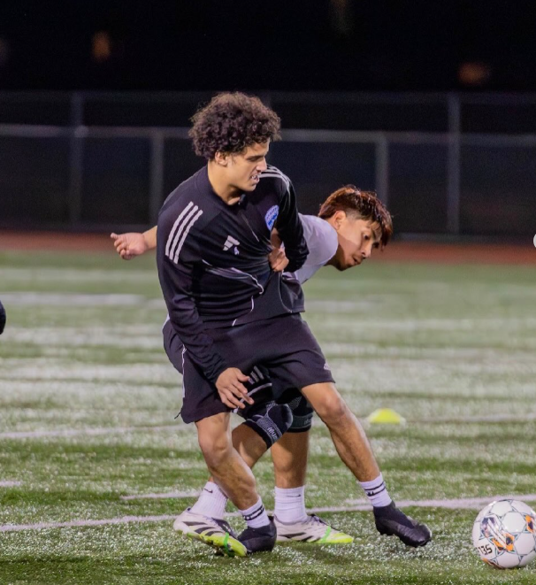 Two soccer players competing for the ball on a field at night.