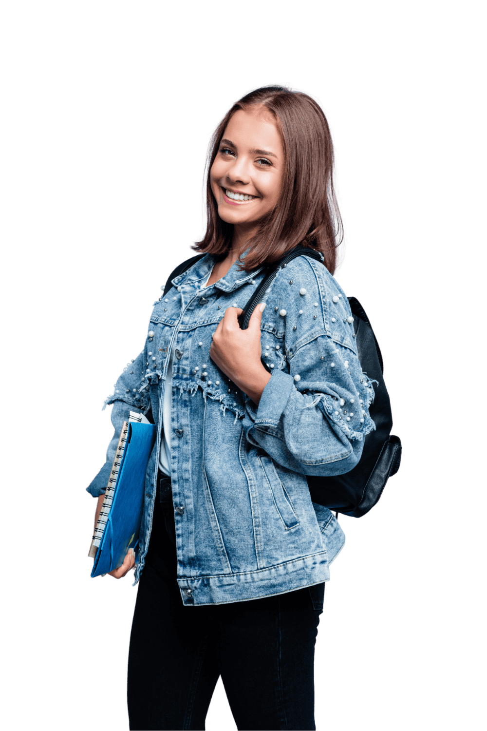 A young woman smiling and holding school books with a backpack, wearing a denim jacket decorated with pearls.