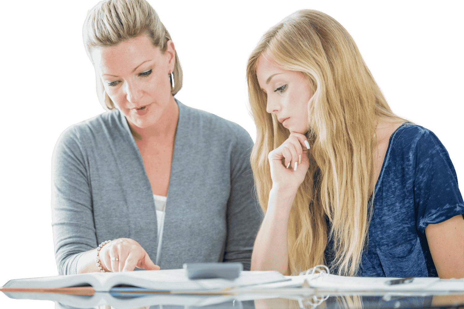 Two women sitting at a table, discussing and reviewing documents together.