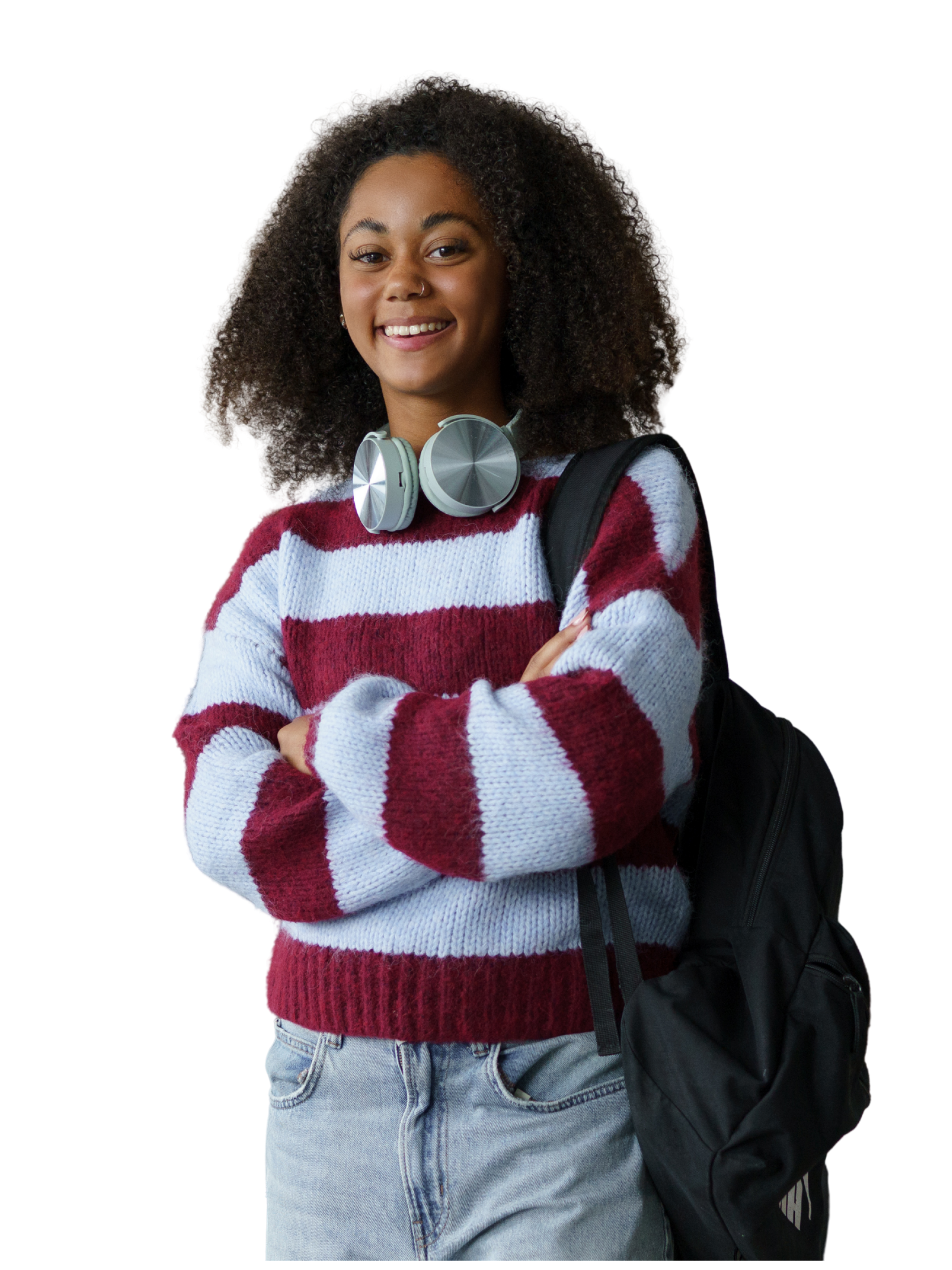 A young woman with curly hair smiling and crossing her arms, wearing a red and white striped sweater, light blue jeans, and a black backpack.