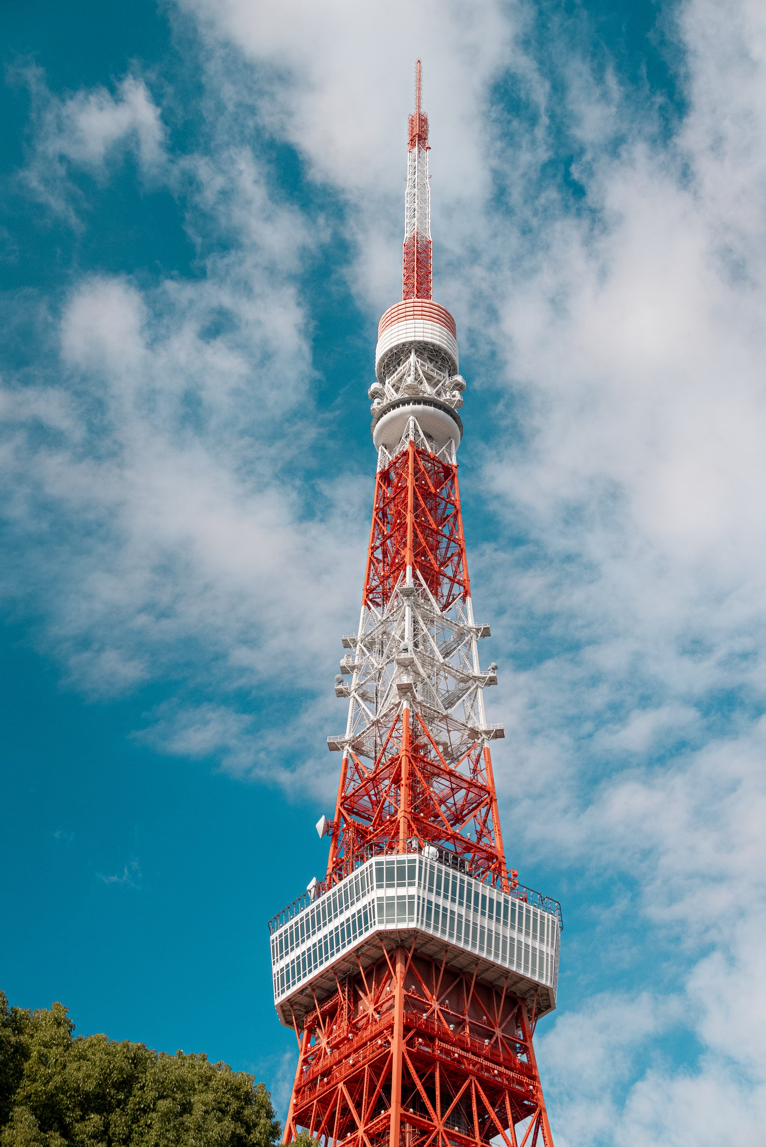 Tour de télévision avec une structure en métal rouge et blanc, sous un ciel bleu avec des nuages.