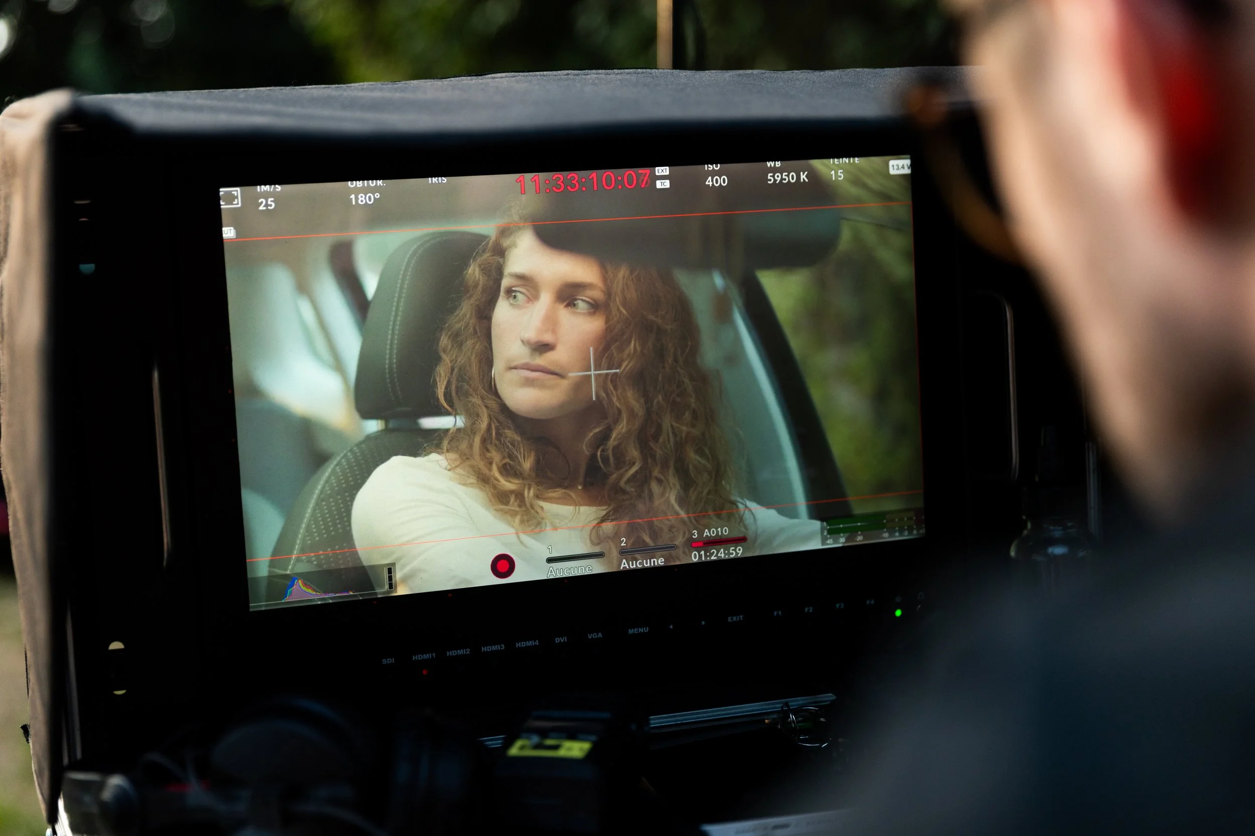 Une femme à l'intérieur d'une voiture, filmée par une caméra de tournage.