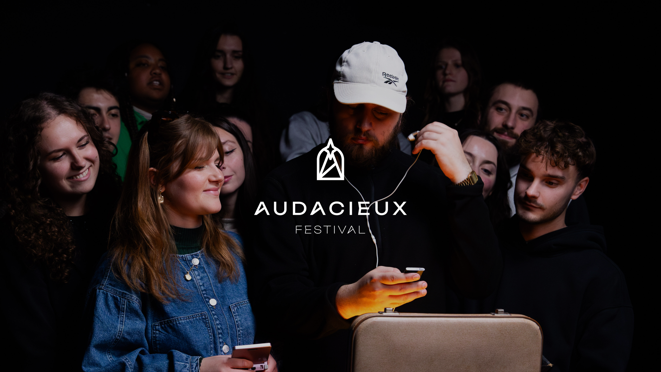 Miniature client : Audacieux festival (photos des membres de l'équipe du festival, il écoutent une musique qui va dévoiler le thème du festival AUDACIEUX, avec logo blanc du client AUDACIEUX FESTIVAL)