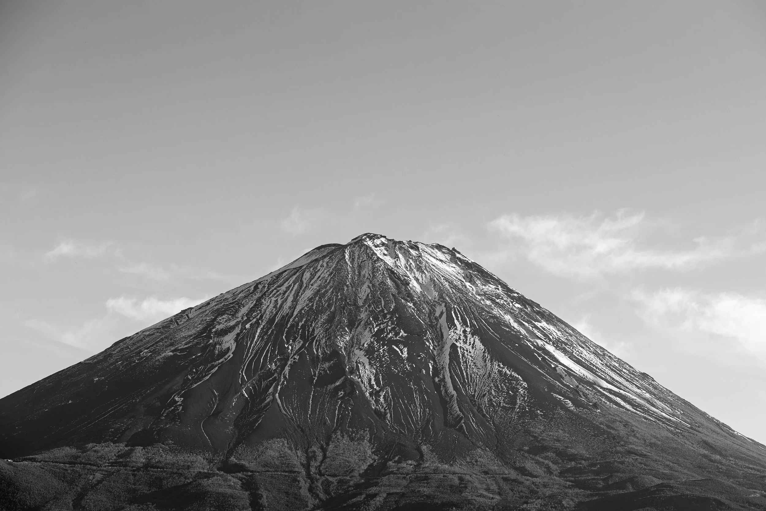Une montagne volcanique avec un sommet enneigé, vue en noir et blanc.