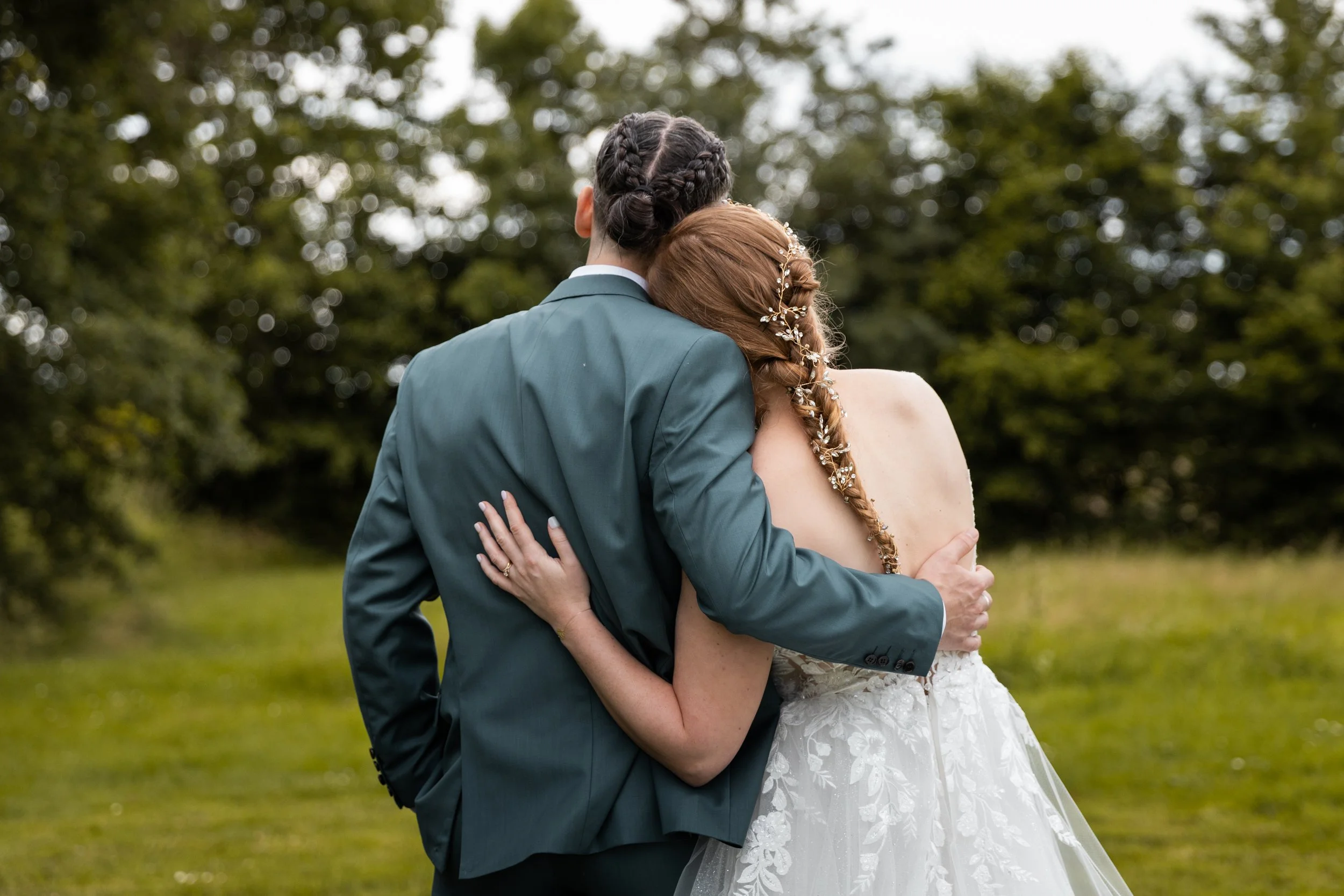 Un couple en robe de mariage et costume s'embrassent dans un parc verdoyant.