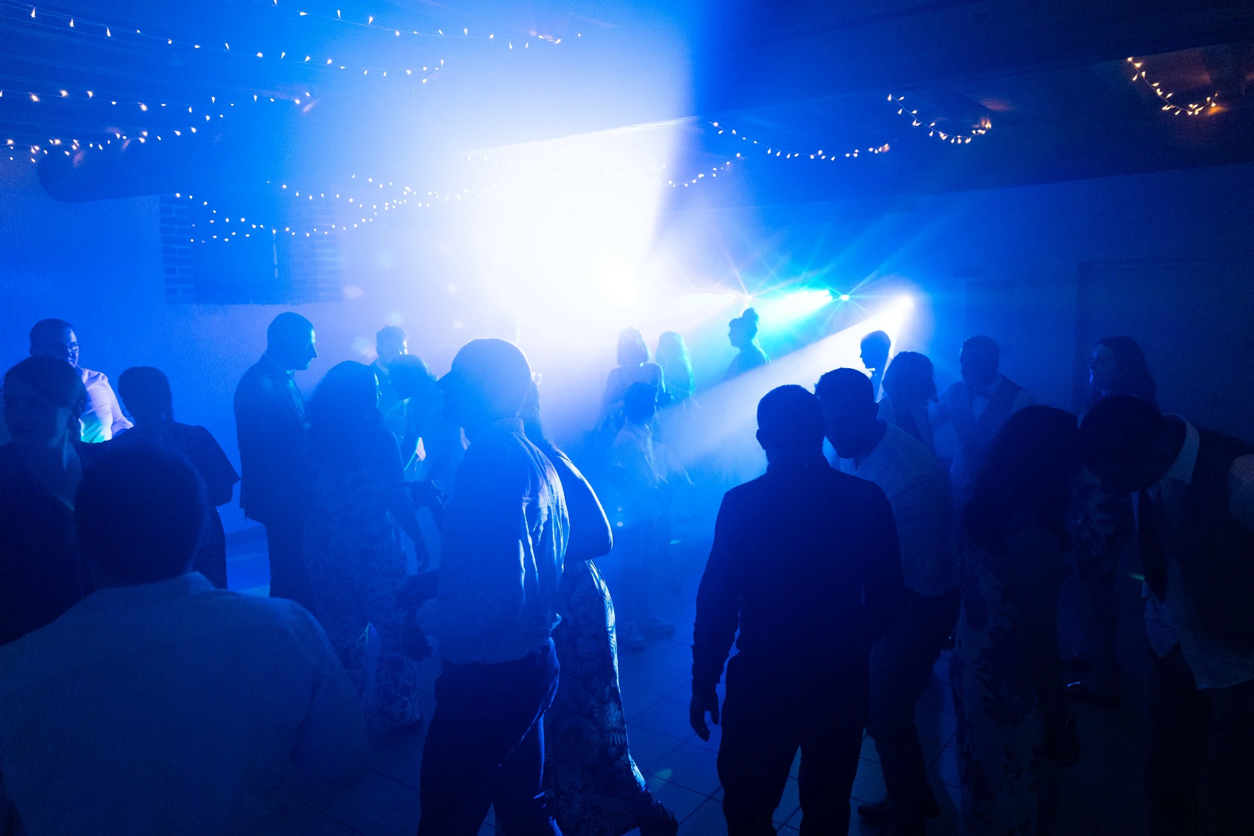 Groupe de personnes dansant lors d'une fête ou d'une discothèque, éclairage bleu avec des lumières scintillantes au plafond.