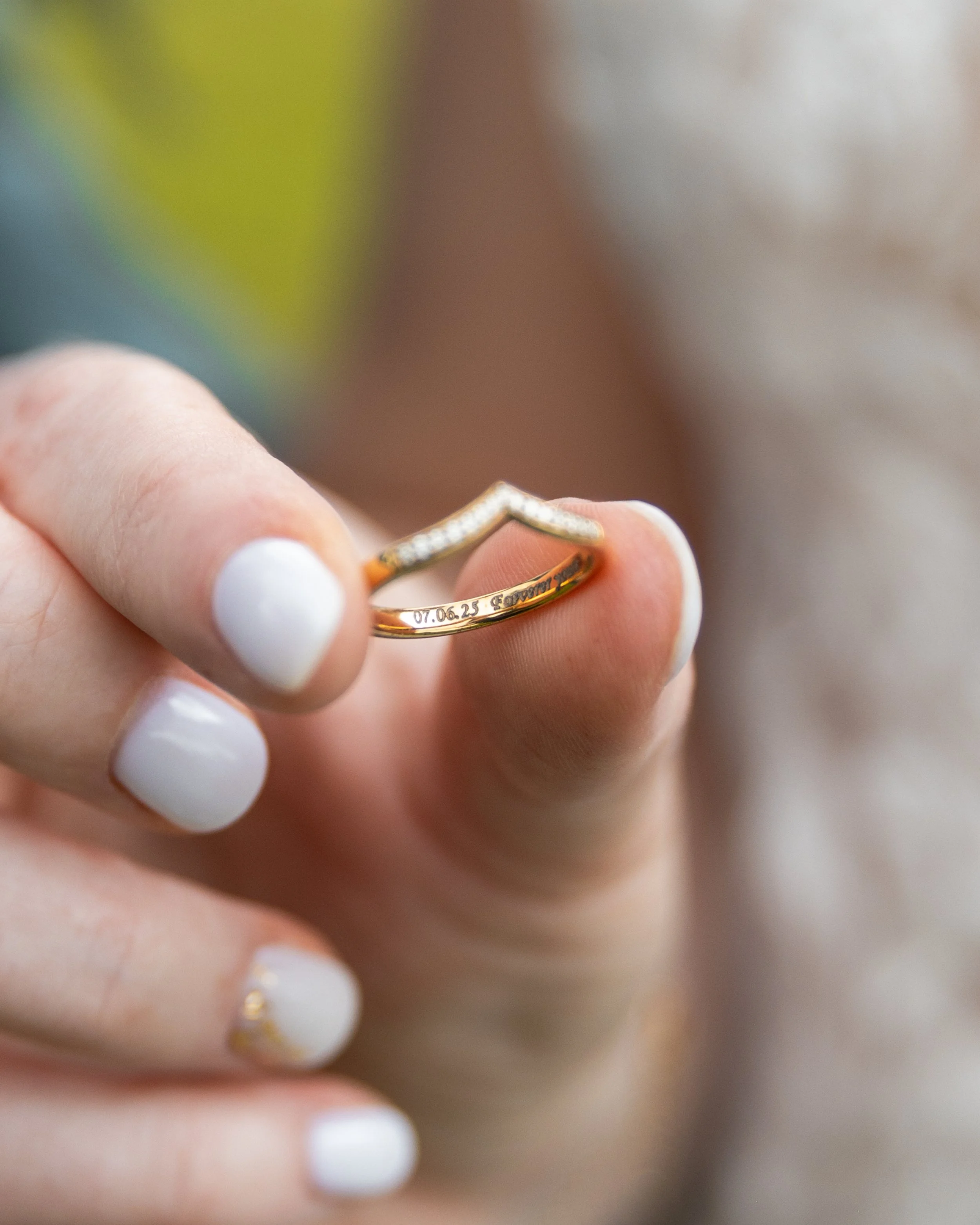 Une main tenant une alliance dorée avec une gravure.