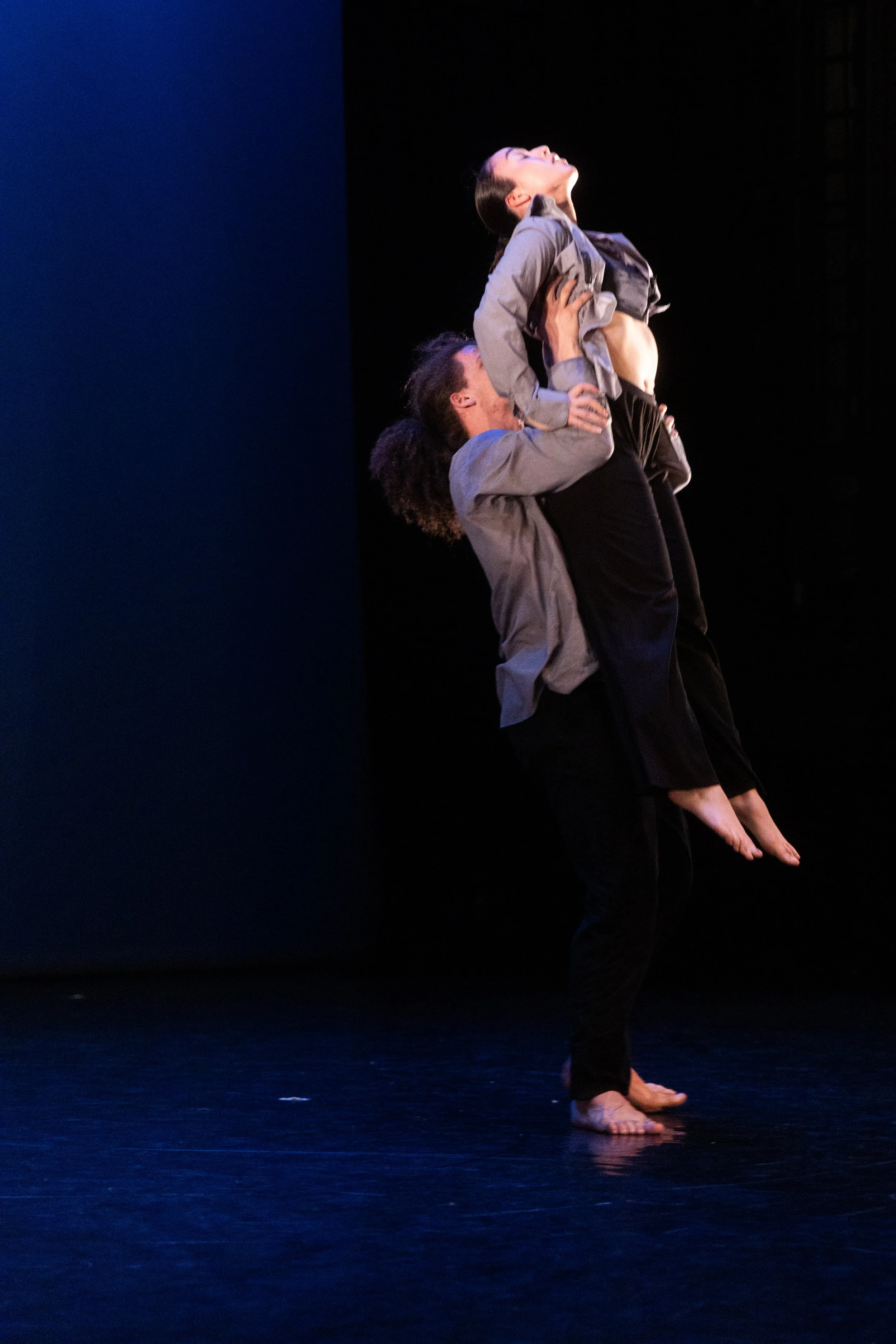 Deux femmes danseuses, l'une en position de levée, l'autre en soutien, dans une scène de danse sur scène noire.