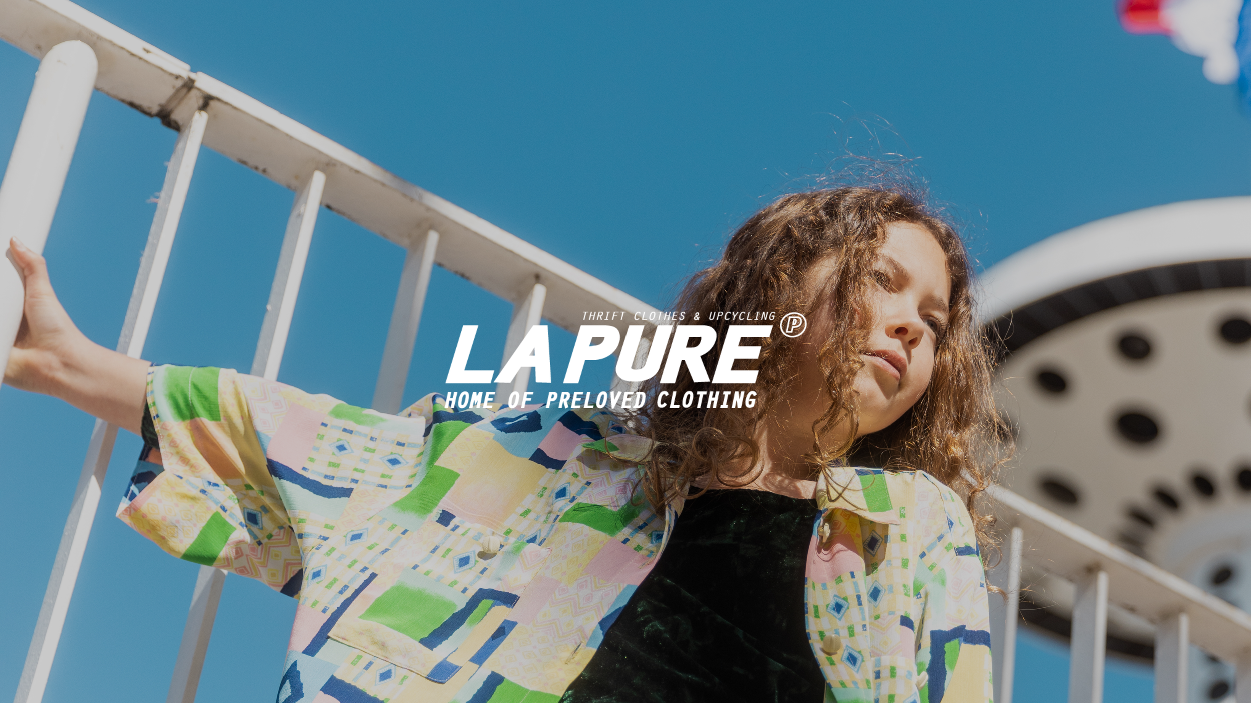Miniature client : La Pure (photo d'un shooting de mode pour enfant, une jeune fille pose sur les quais de Lyon, elle regarde au loin et elle porte les vêtements de la marque LAPURE, pour la selection enfants, selection kids, avec logo blanc LAPURE)
