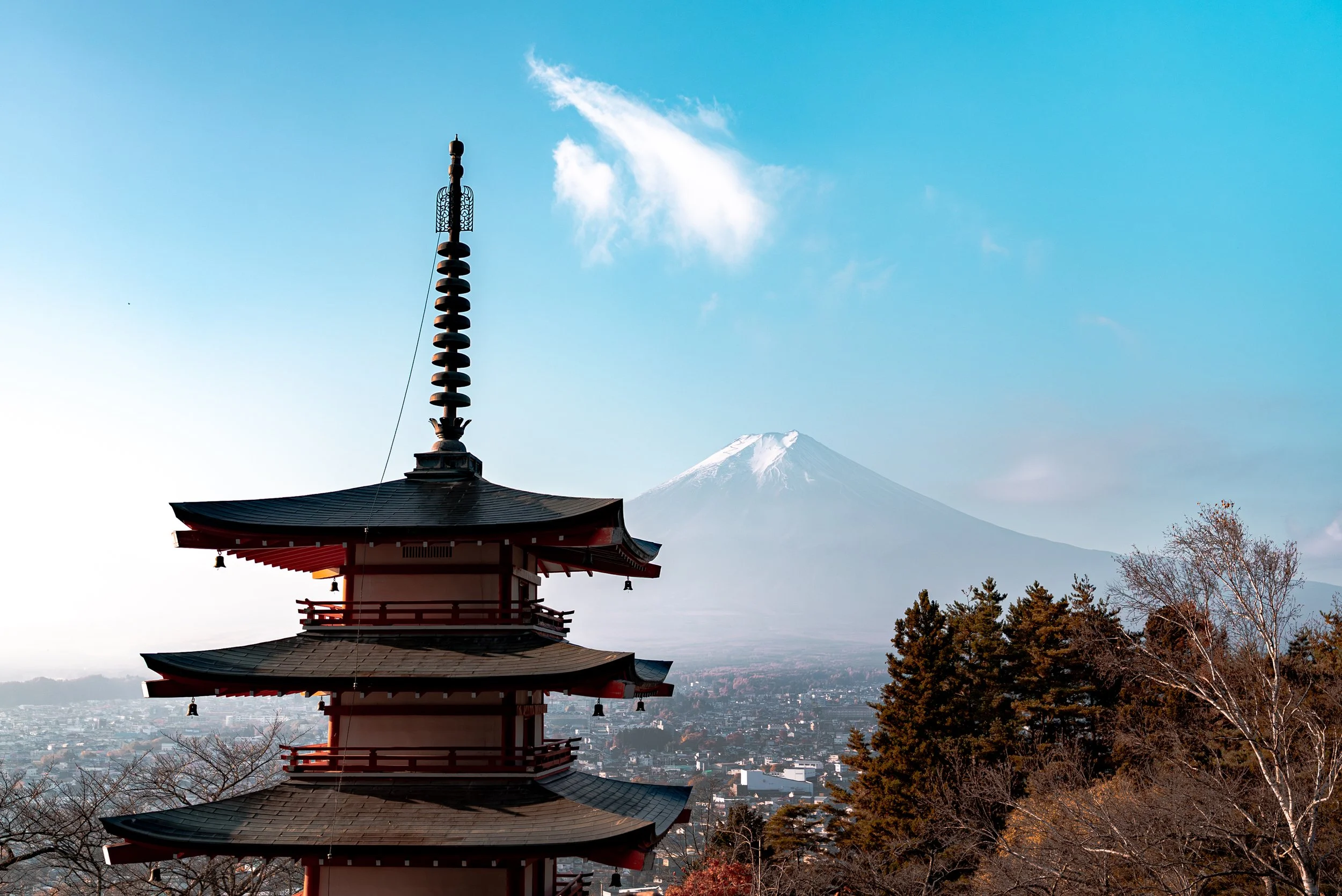 Pagode traditionnelle japonaise avec Mont Fuji enneigé en arrière-plan, ciel bleu et quelques nuages.