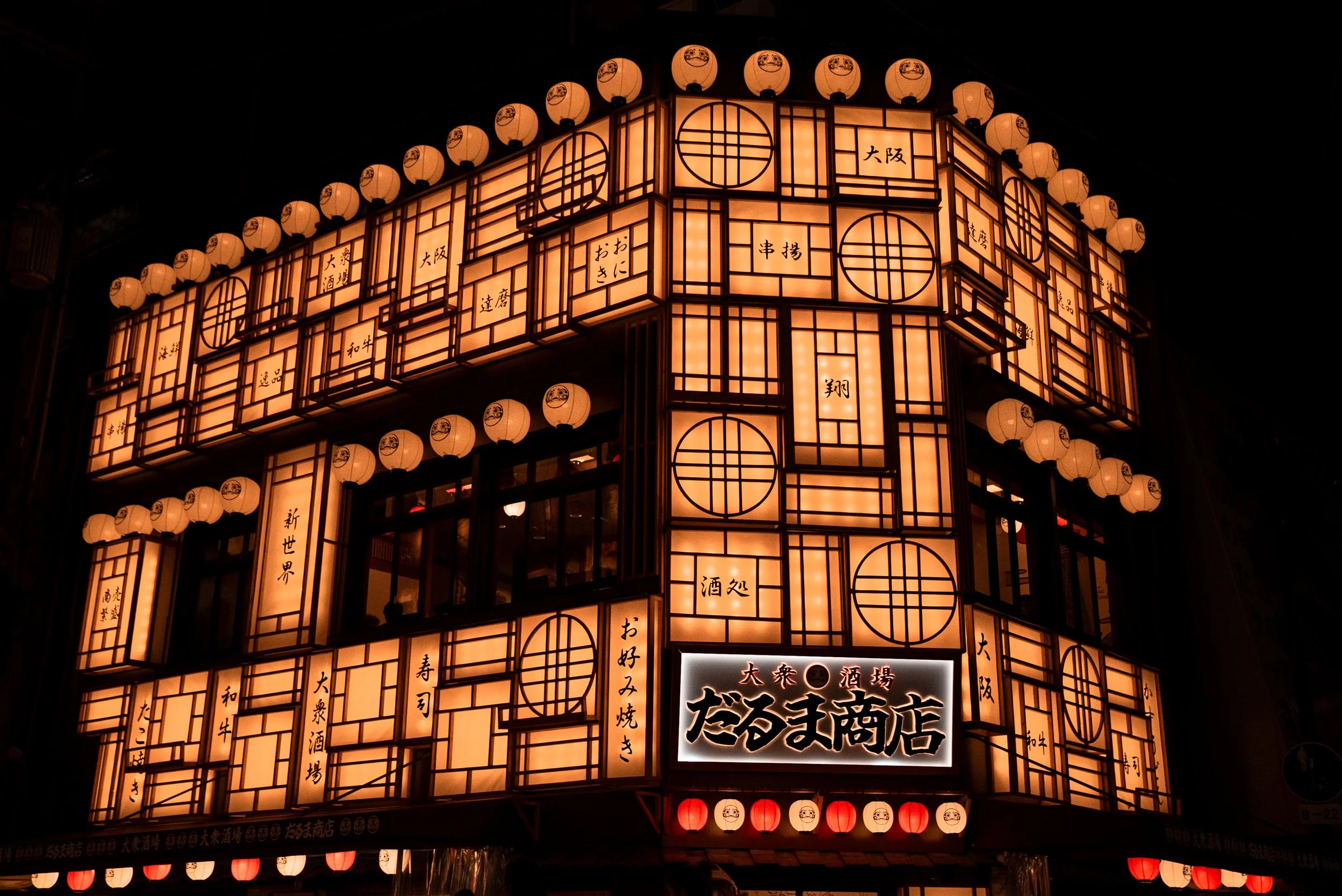 Façade d'un restaurant ou d'un magasin orné de lanternes japonaises lumineuses avec des caractères japonais.