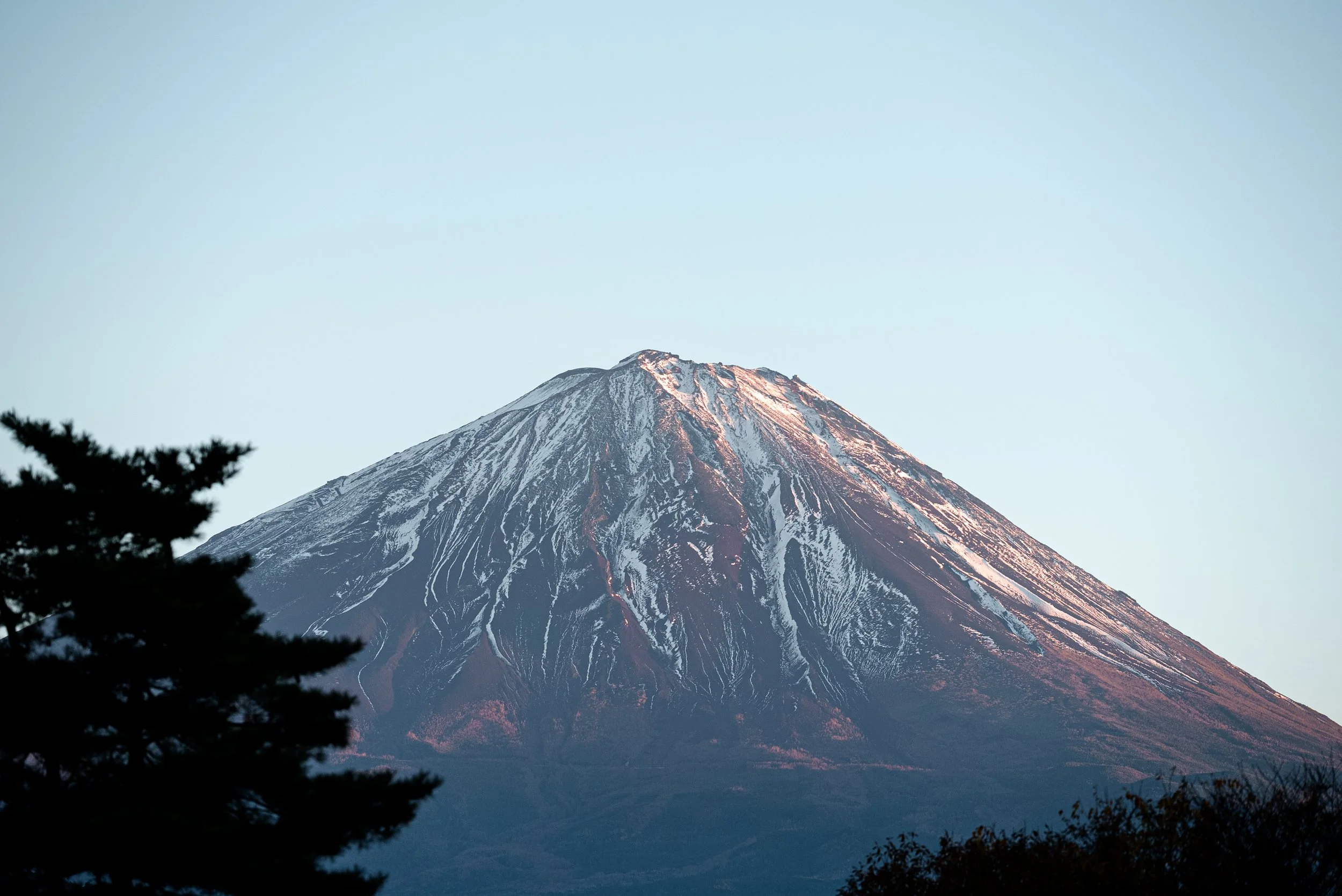 Montagne avec sommet enneigé vue du bas contre un ciel clair.