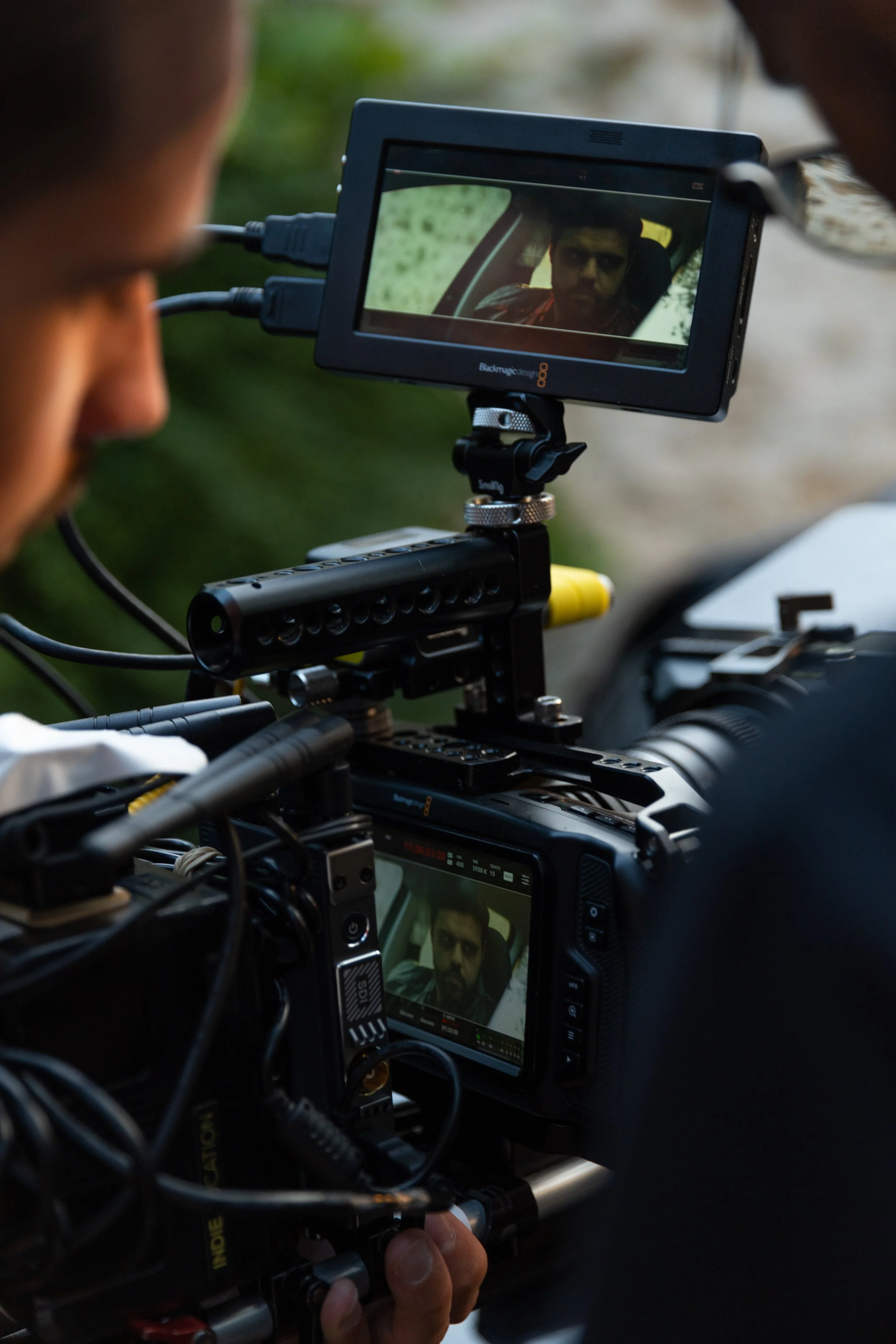 Un opérateur de caméra filme un homme à l'intérieur d'une voiture, visible à l'écran de la caméra.