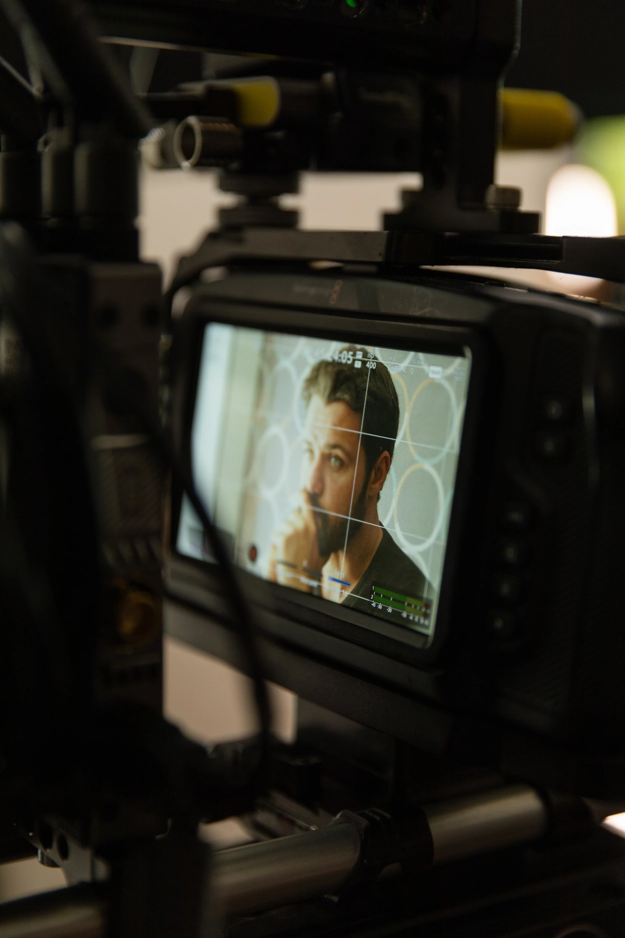 Prise de vue d'un homme à travers l'écran d'une caméra de tournage, le regard pensif, en train de réfléchir ou d'attendre.