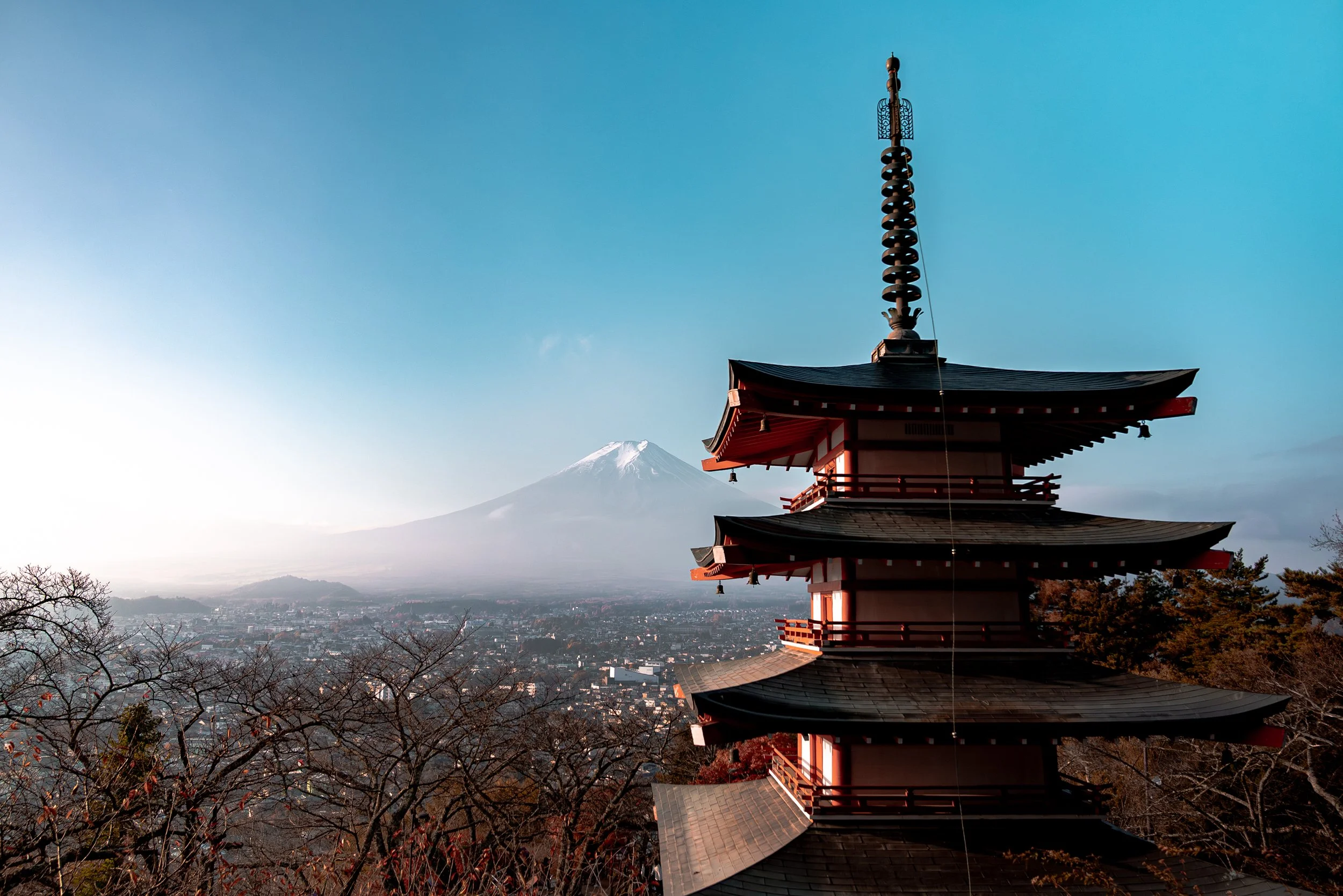 Pagode traditionnelle japonaise avec Mont Fuji en fond, arbres et ville au premier plan.