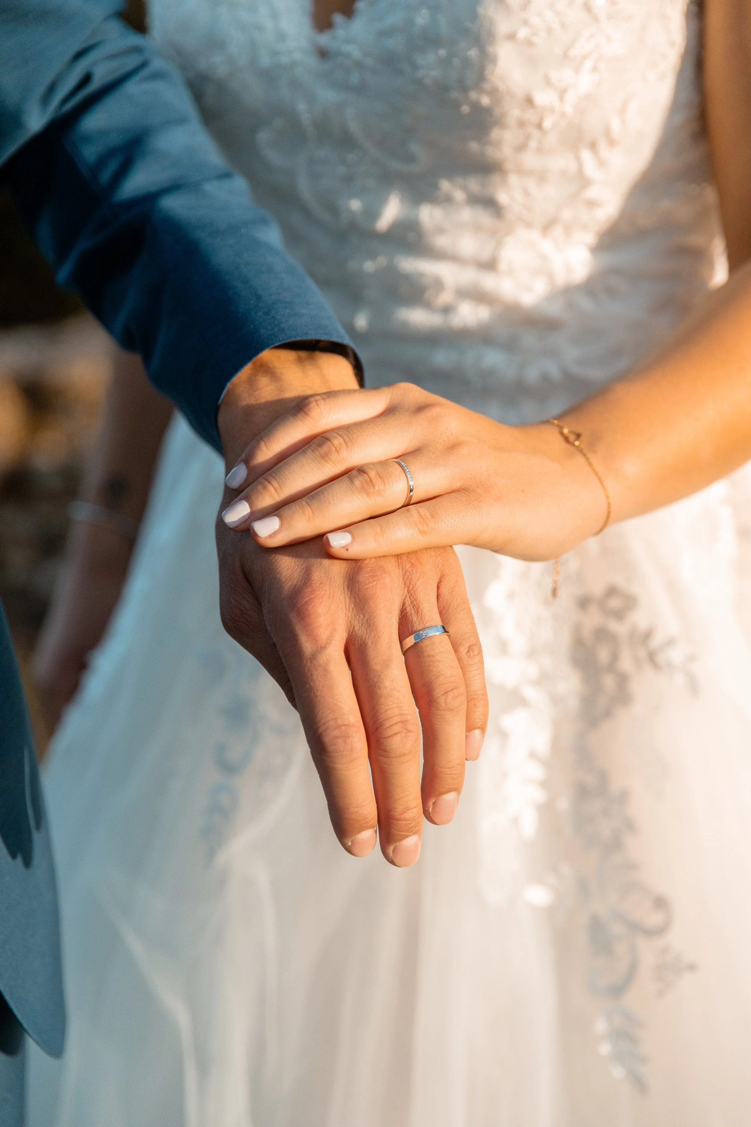 Les mains d'un couple avec des alliances de mariage, mains jointes, lors de leur mariage.