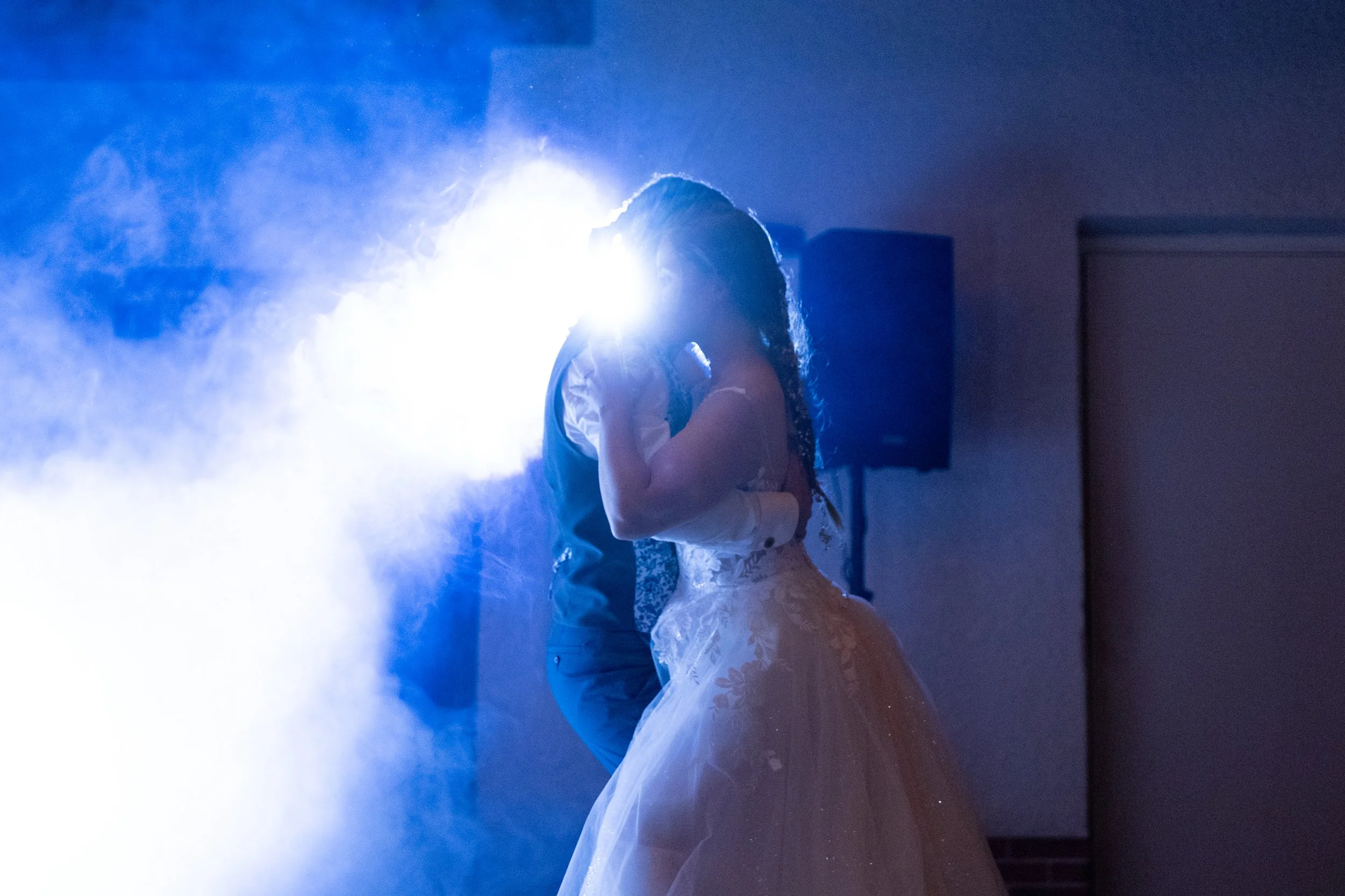 Un couple danse lors de leur mariage avec des effets de fumée et de lumière bleue
