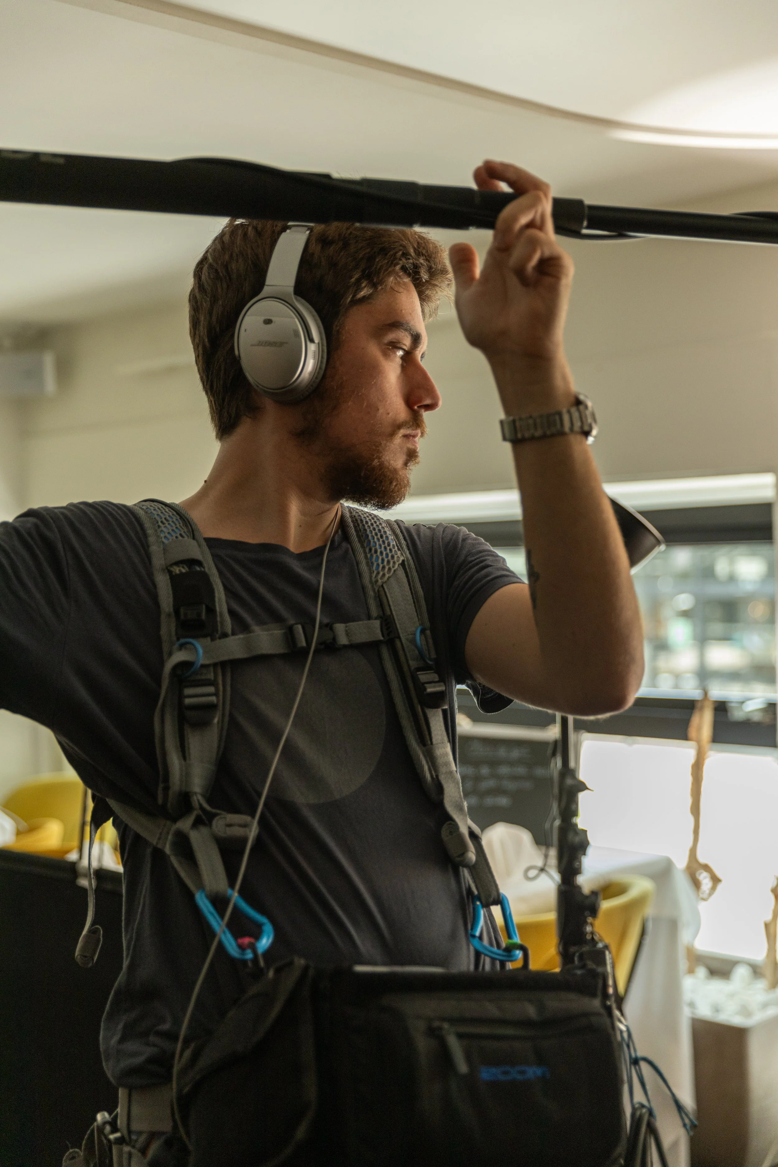 Un homme portant un casque audio et un sac à dos ajuste un support dans une pièce bien éclairée.