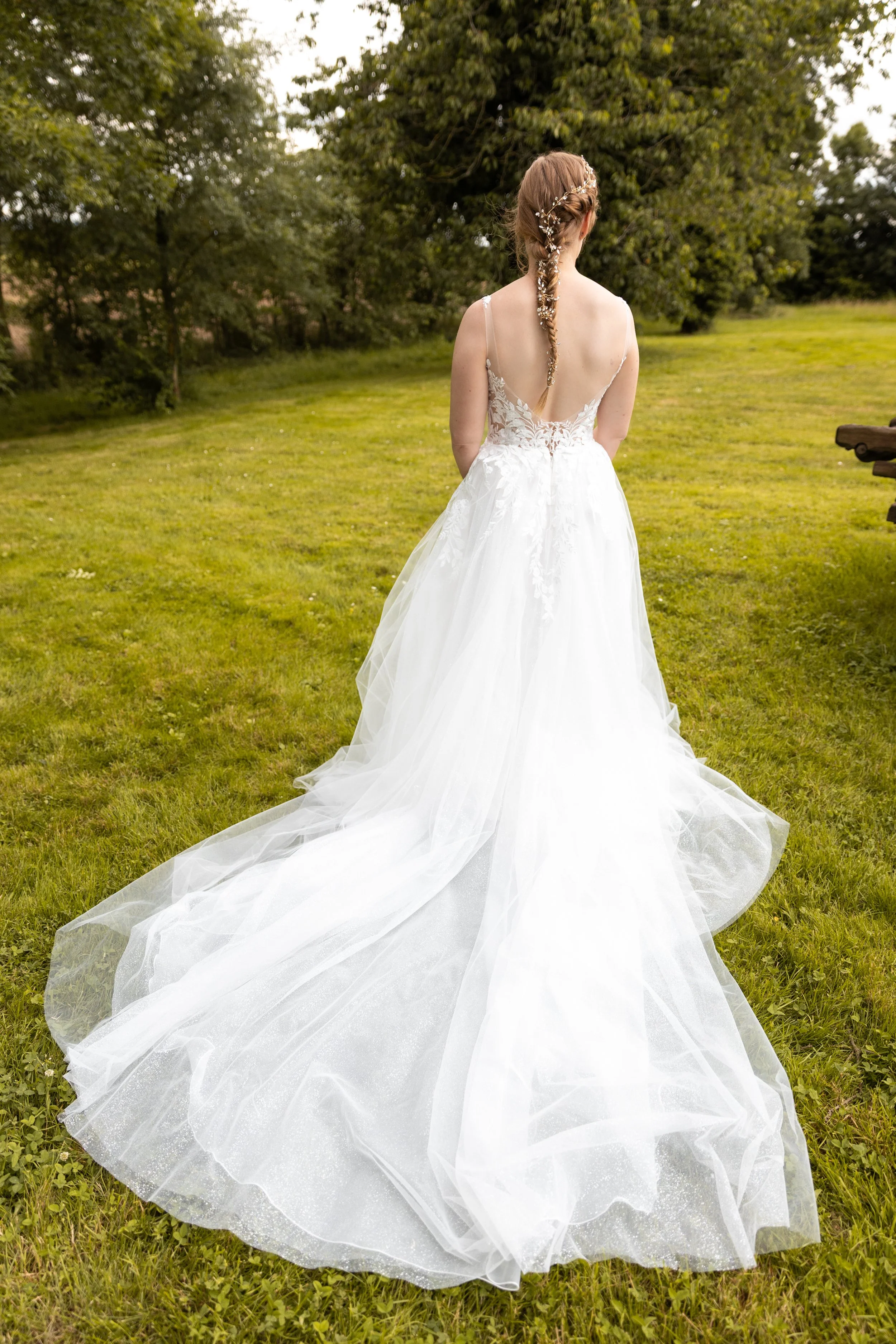 Une mariée vue de dos dans une robe de mariage blanche, avec un jardin vert en arrière-plan.