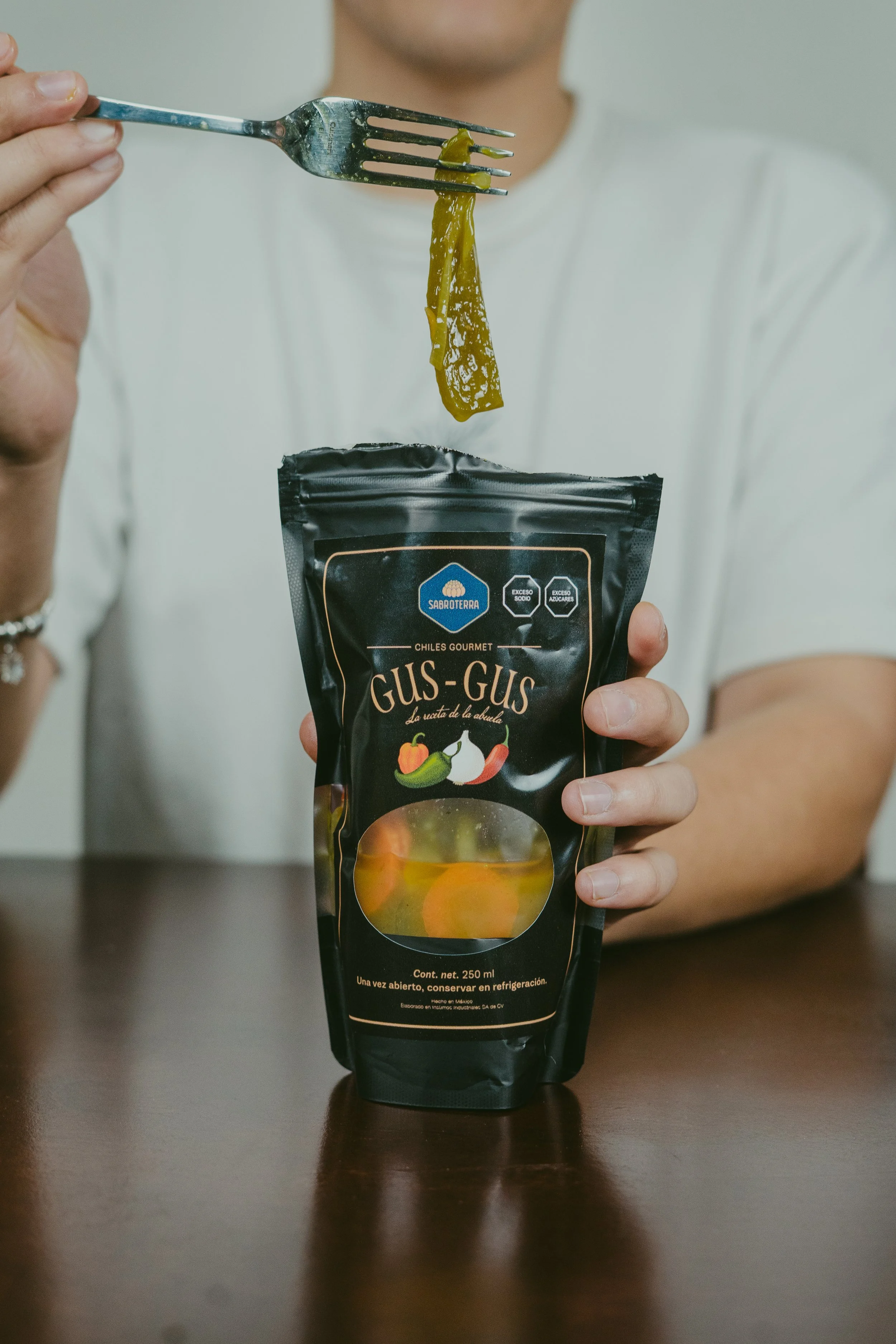 Persona sosteniendo un paquete de Gus-Gus, una bebida enlatada, con un tenedor y una porción de gelatina de color amarillo.