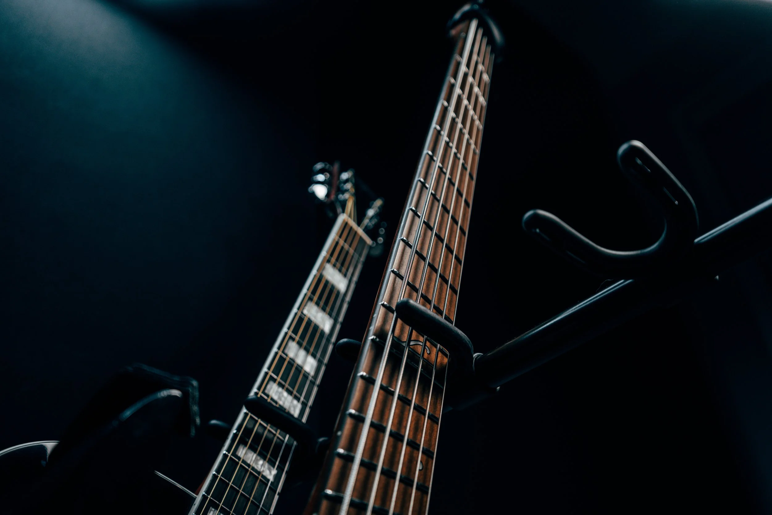 Close-up of one acoustic guitar and bass mounted on a black wall, captured from a low angle.
