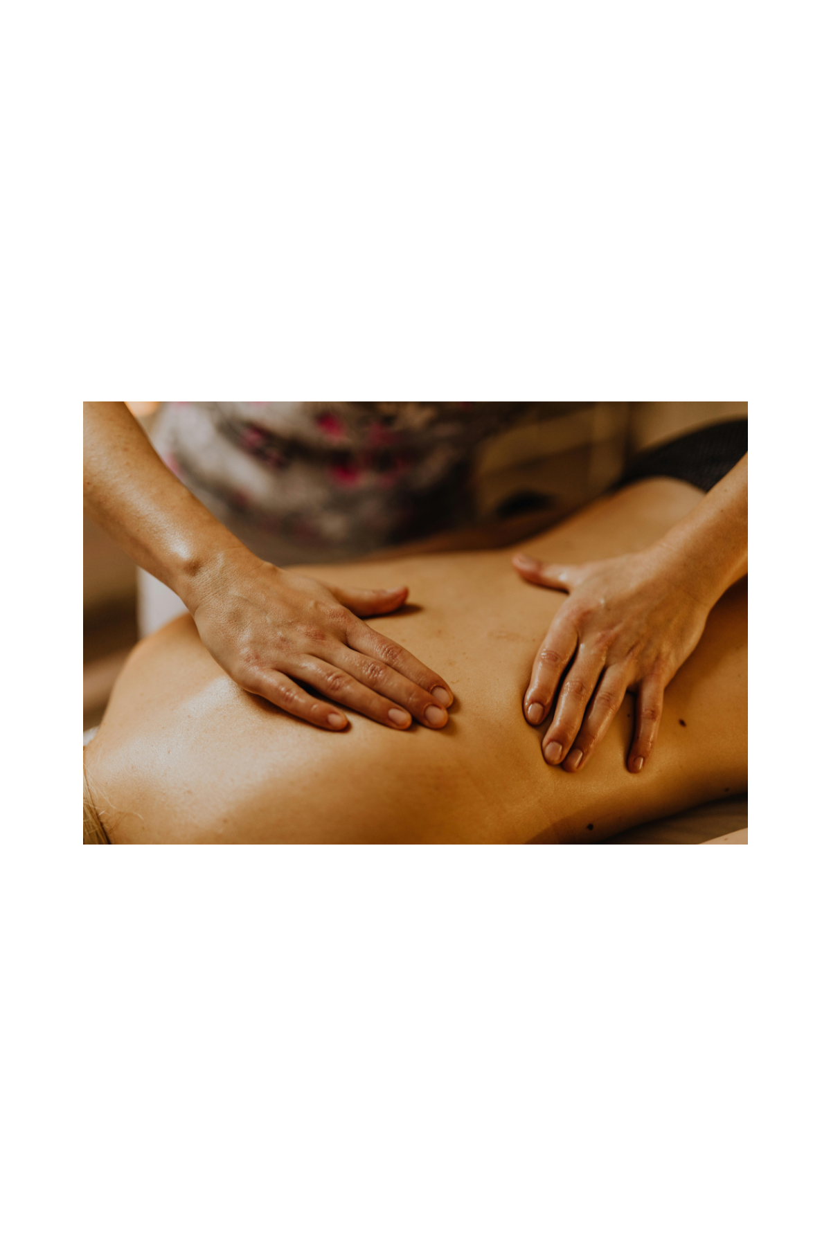 A person receiving a massage on their back with hands applying pressure, in a spa or massage therapy setting.