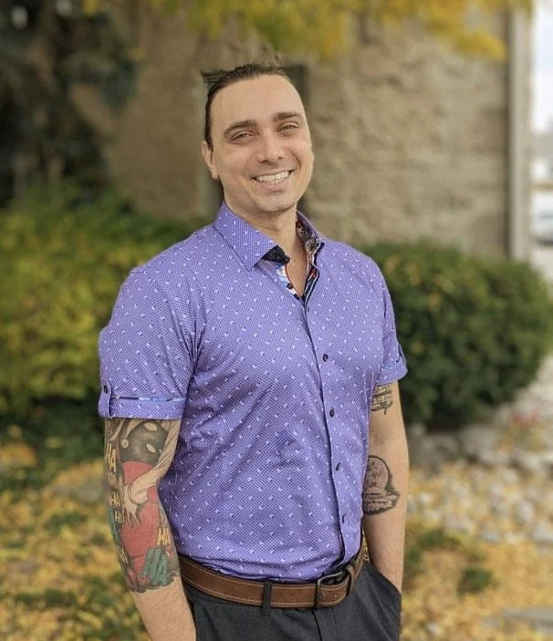 Osteopath Mitch Forster smiling in an outdoor setting with a purple button down shirt.