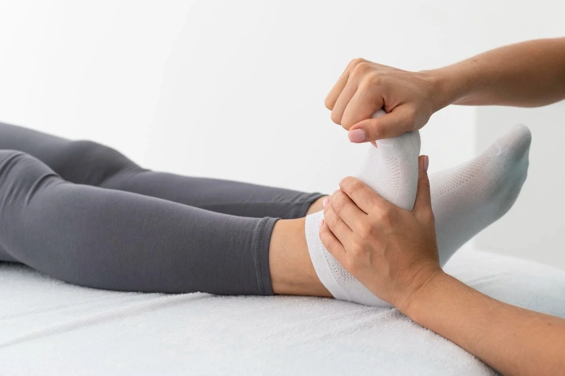A person receiving physical therapy for an ankle injury, with a healthcare professional holding their ankle and applying manual therapy.
