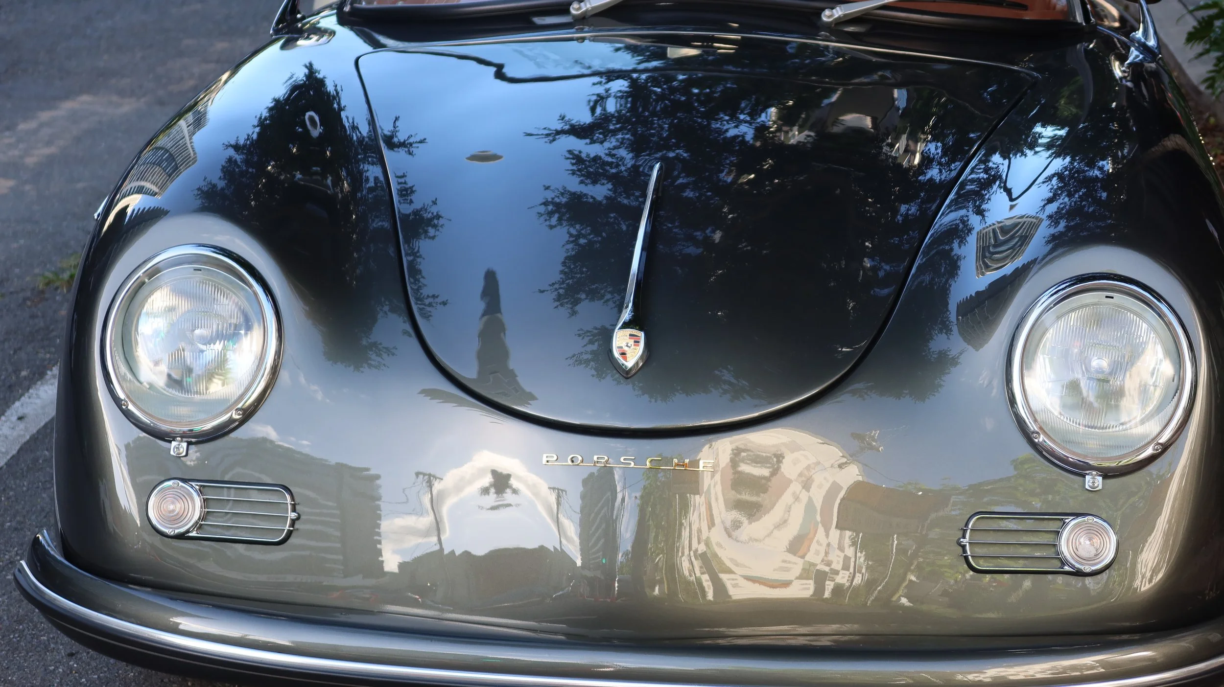 Close-up of the front of a black Porsche sports car, showing the hood, headlights, and Porsche emblem.