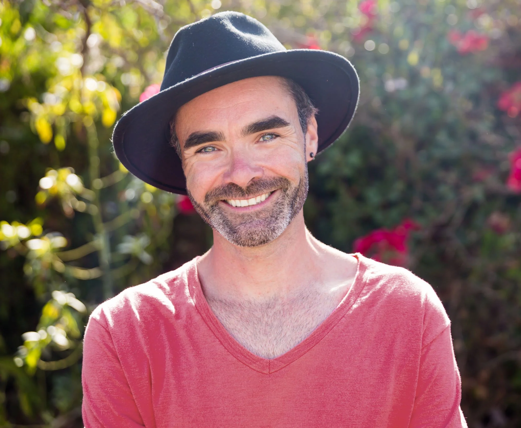 Alex Wood smiling in a red shirt and fedora