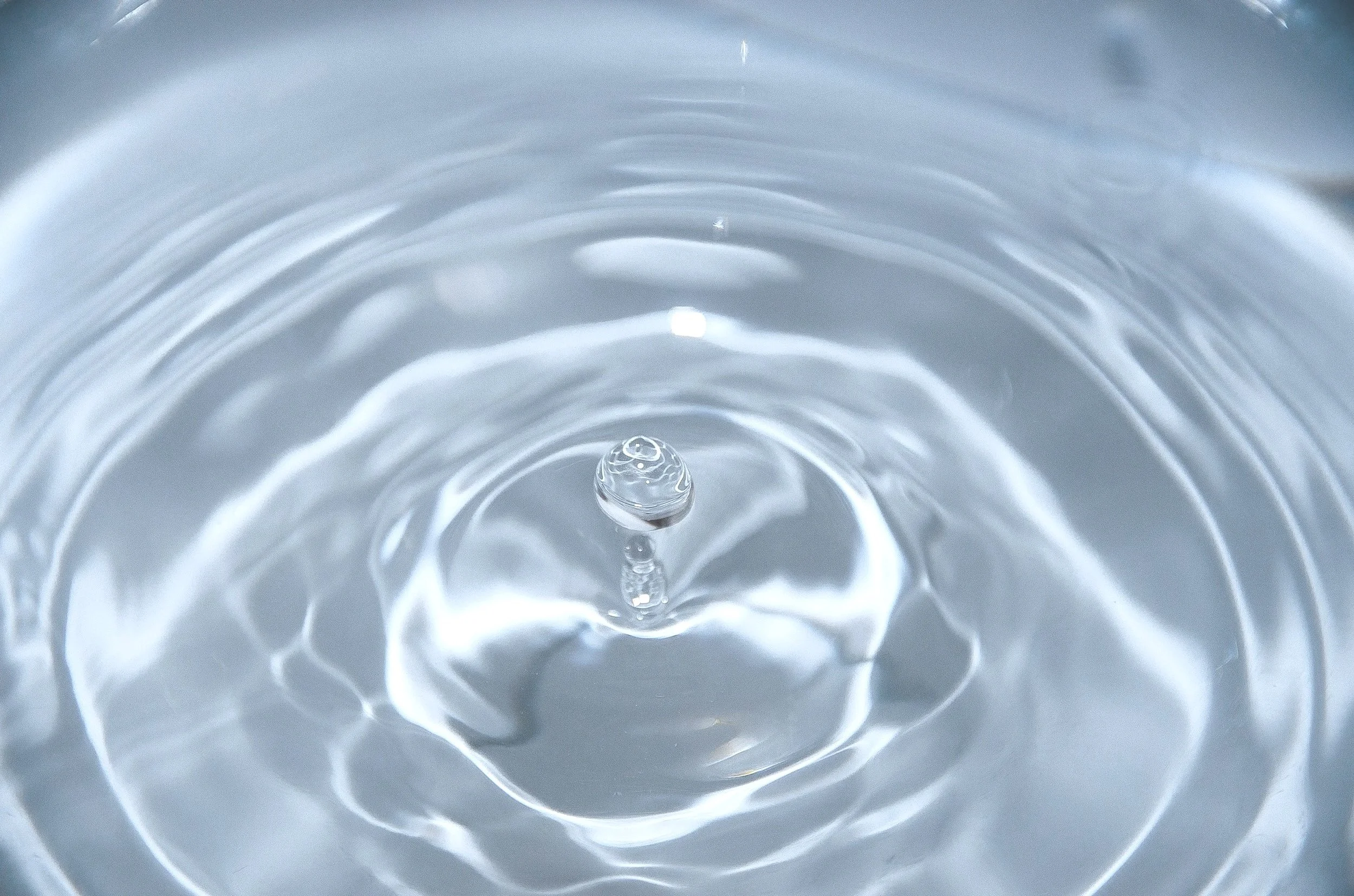 Close-up of a water droplet creating ripples on the surface of a body of water.