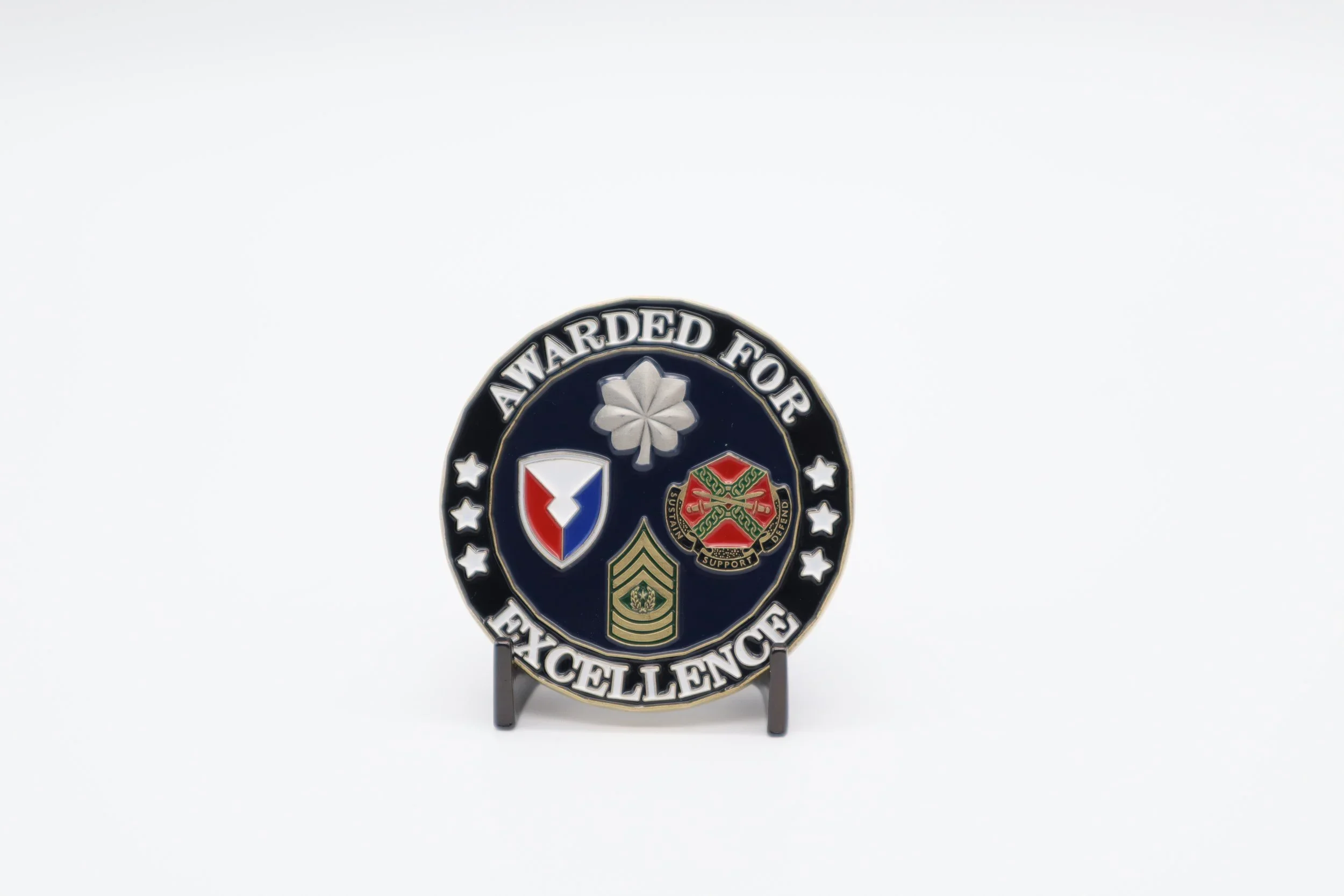 Medal with a black background reading 'Awarded for Excellence' with various emblems and symbols, including a flower, stars, a shield, and a crest, mounted on a stand.