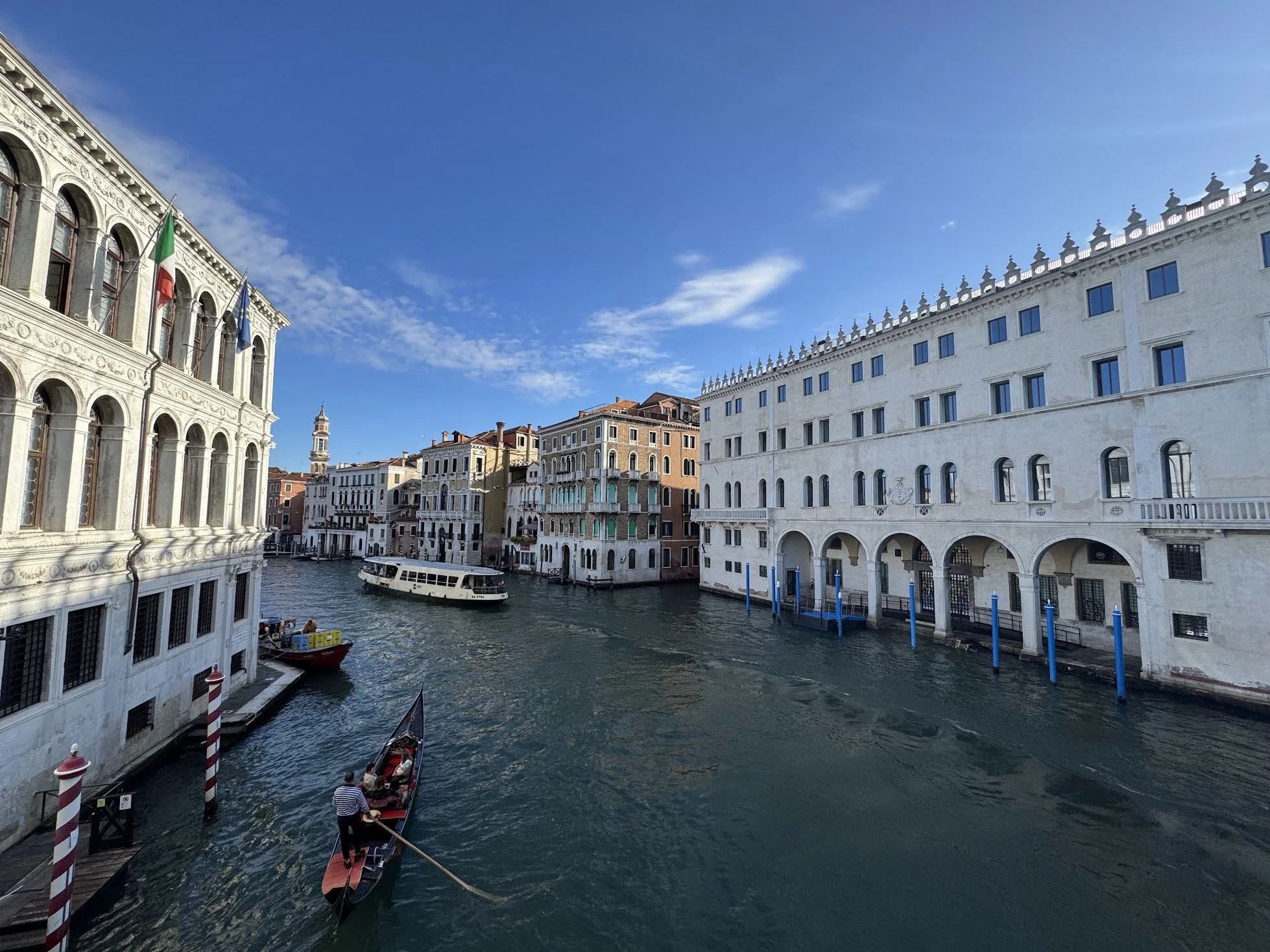 View of a canal in Venice, Italy, with traditional buildings on either side and a boat cruising through the water.