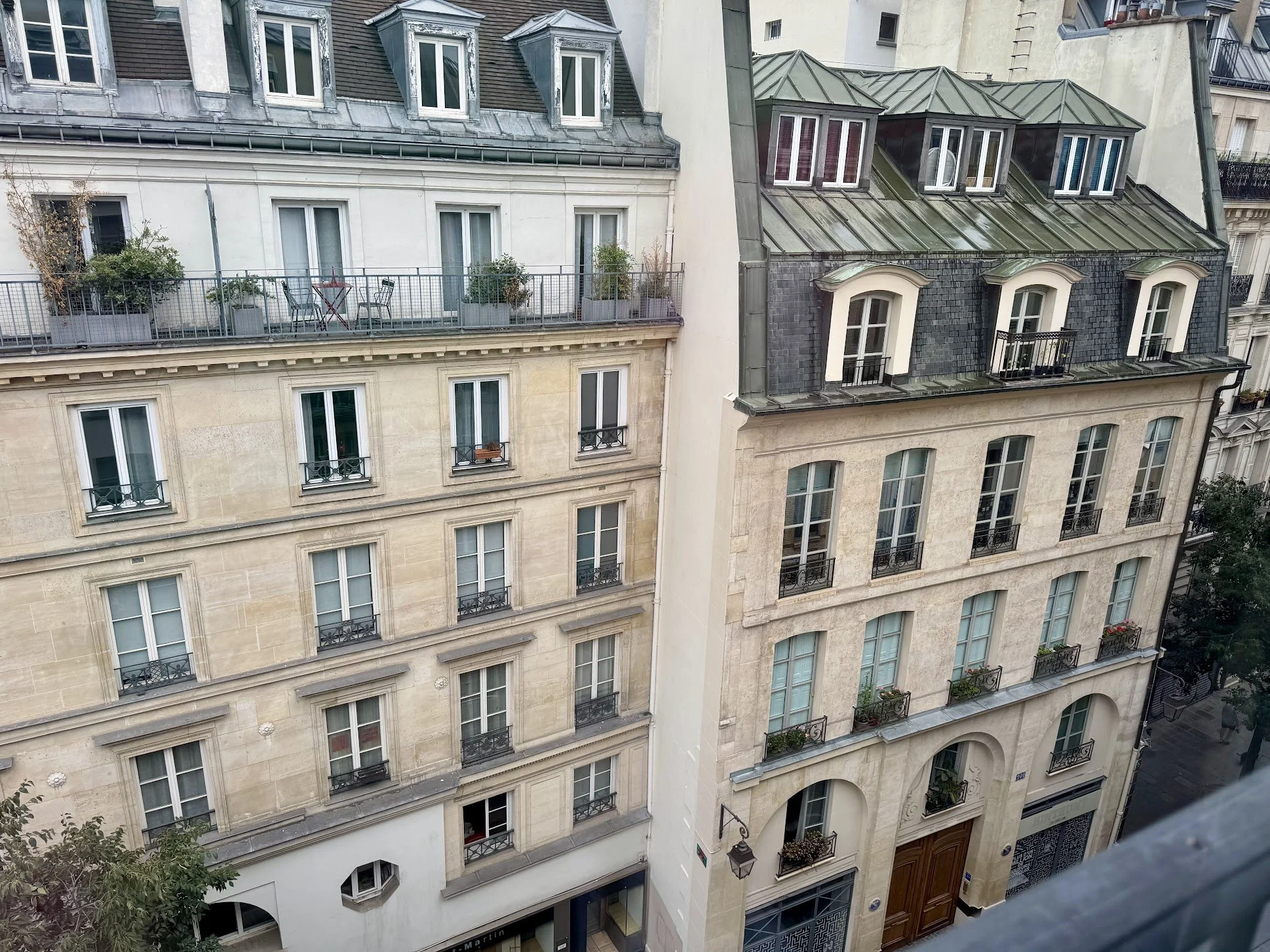 View of multiple apartment buildings with windows, balconies, and rooftops in an urban setting.