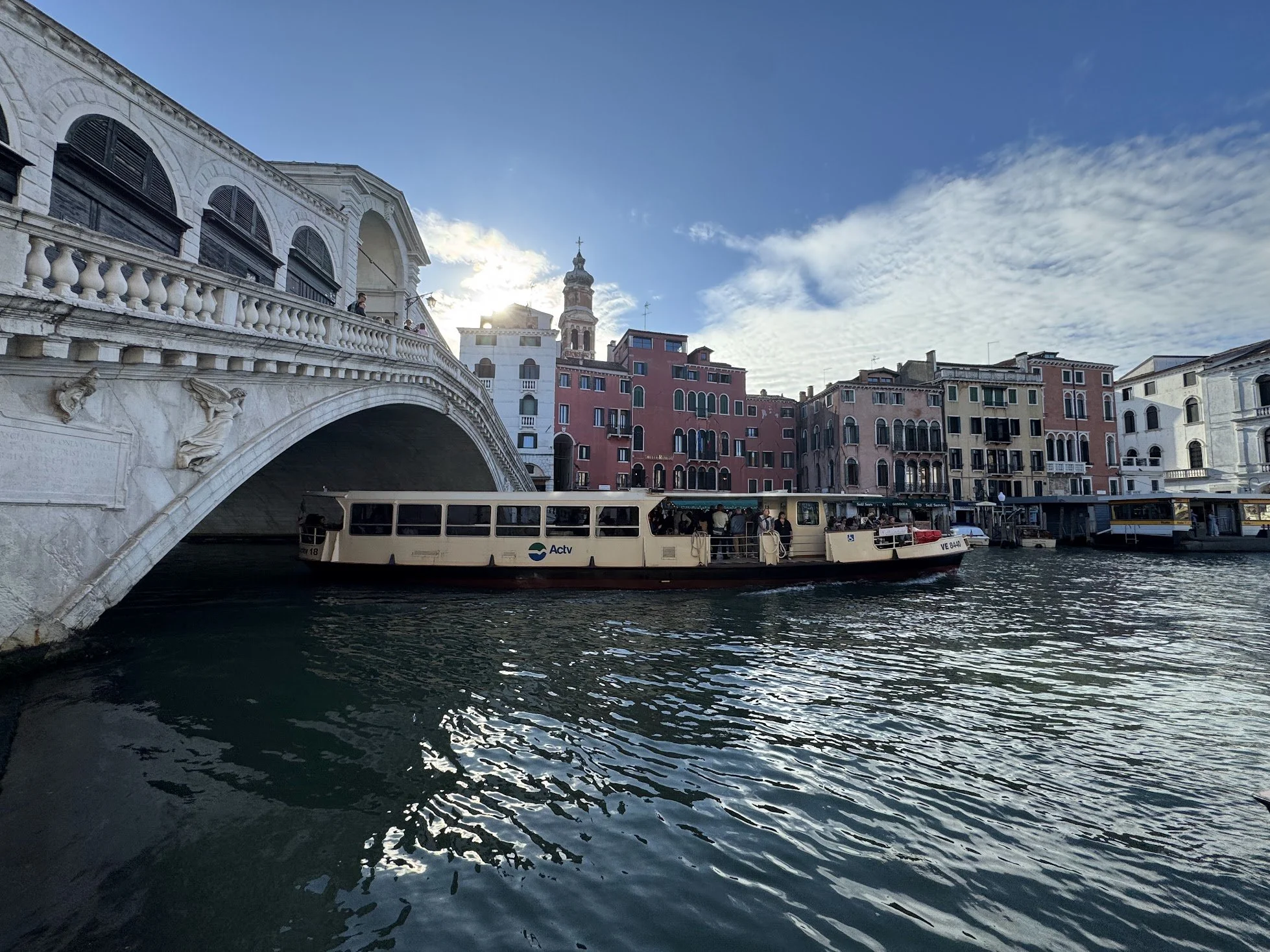 A canal in Venice, Italy, with colorful buildings along the water and a boat carrying passengers.
